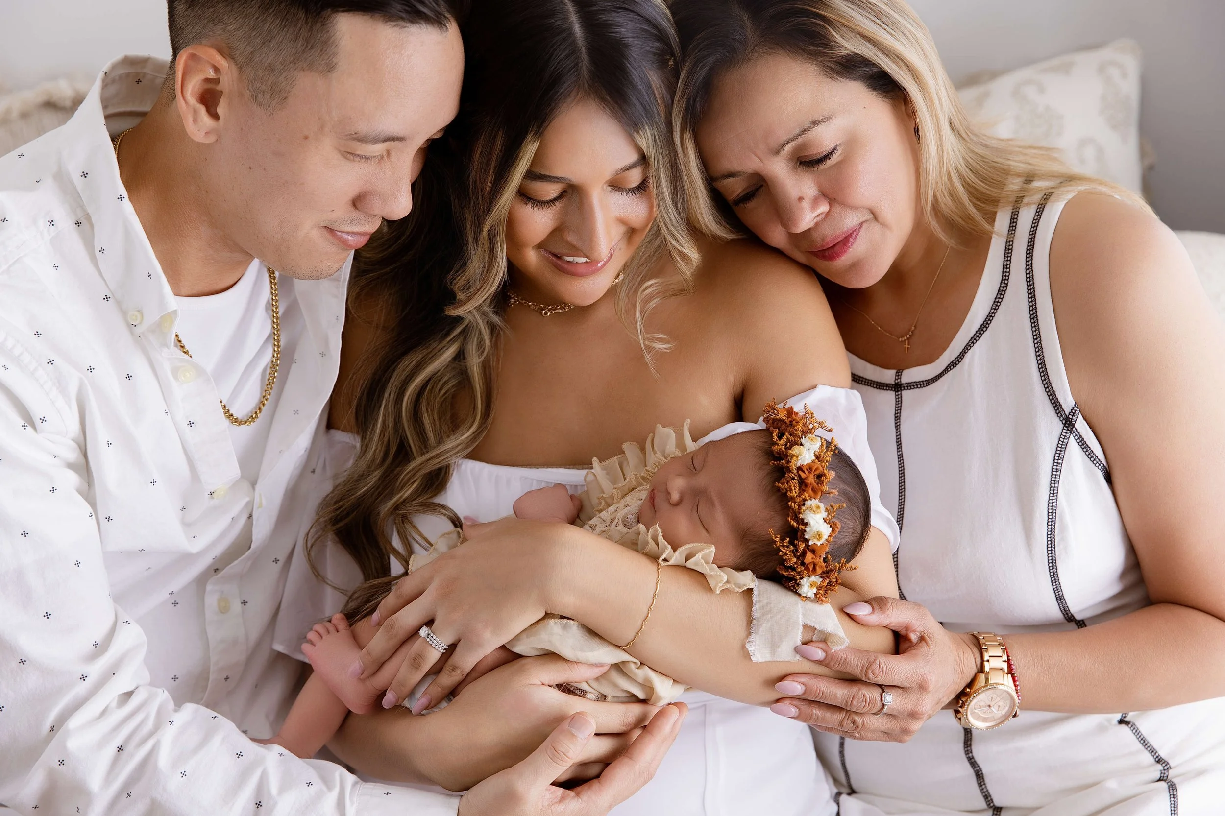 Newborn family portrait featuring parents and a loved one holding their baby during a studio photography session