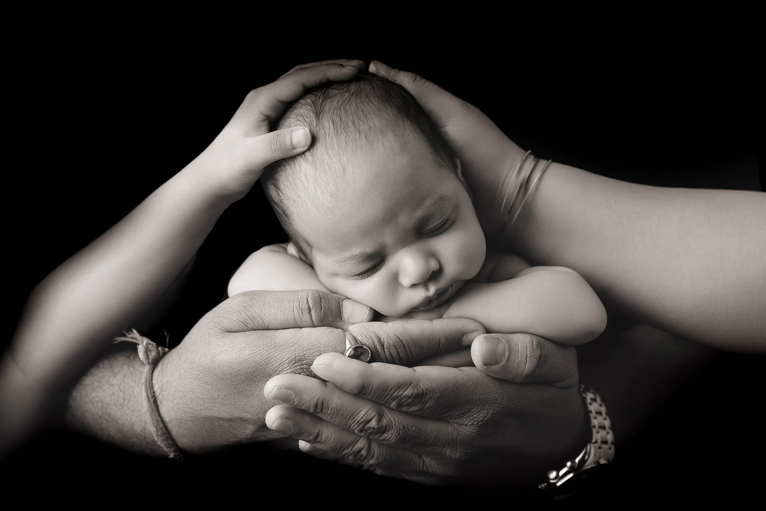 black and white newborn baby in dad's hands and family