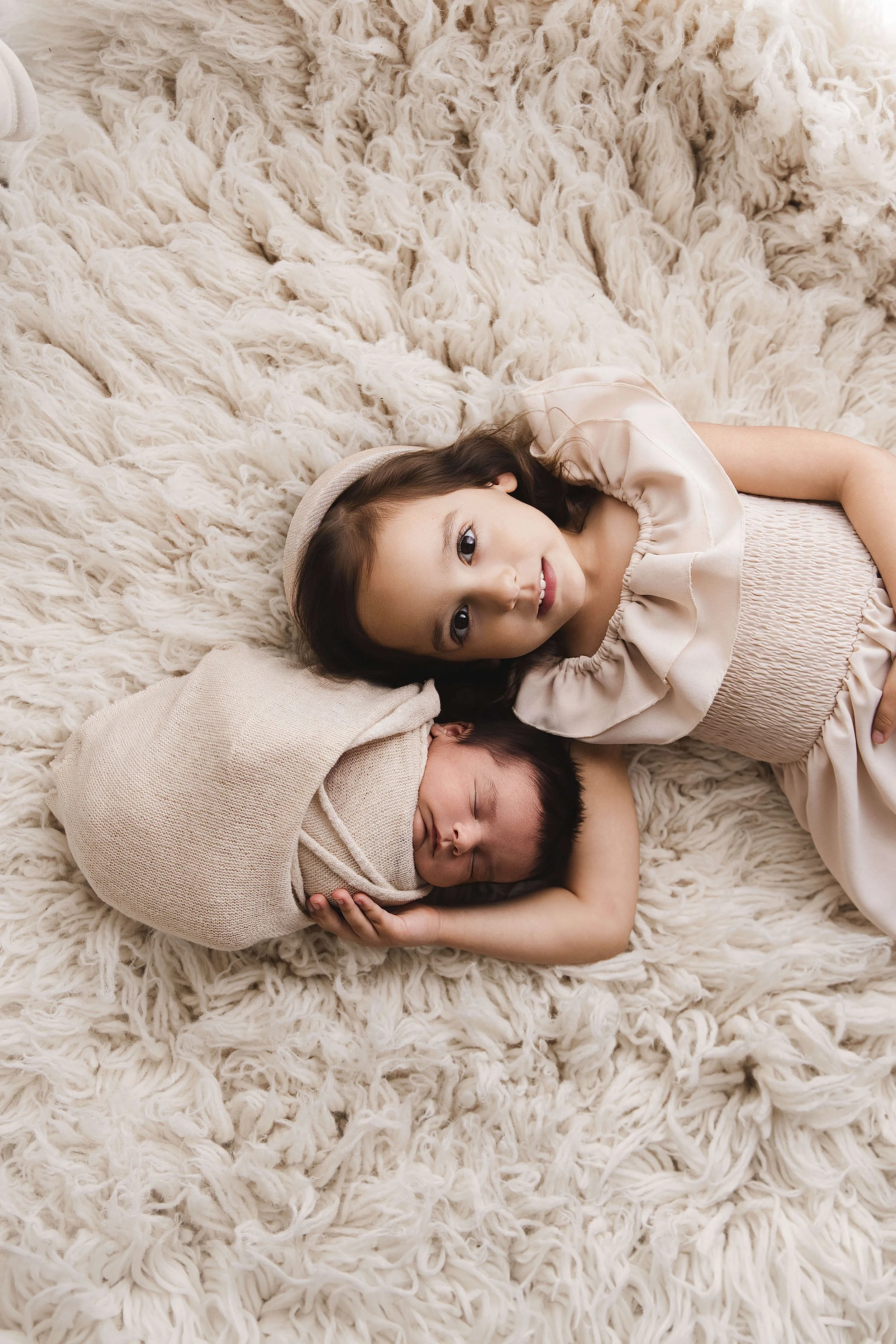 Older sister laying down with newborn brother neutral