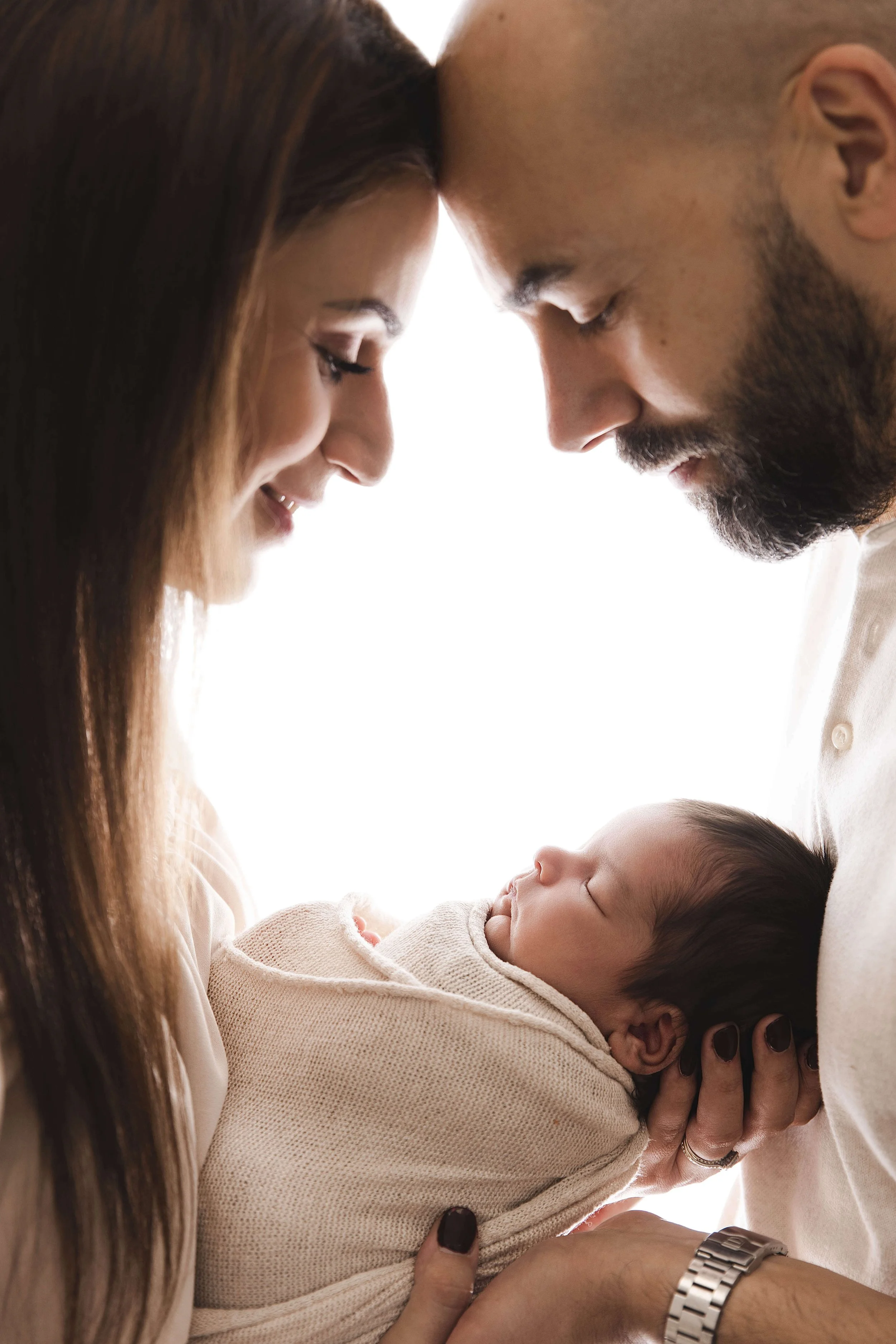 parents with light behind them looking down at baby boy