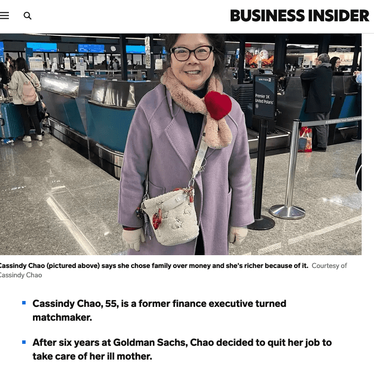 A woman in a purple coat with a beige scarf and red heart-shaped accessory at an airport check-in counter.