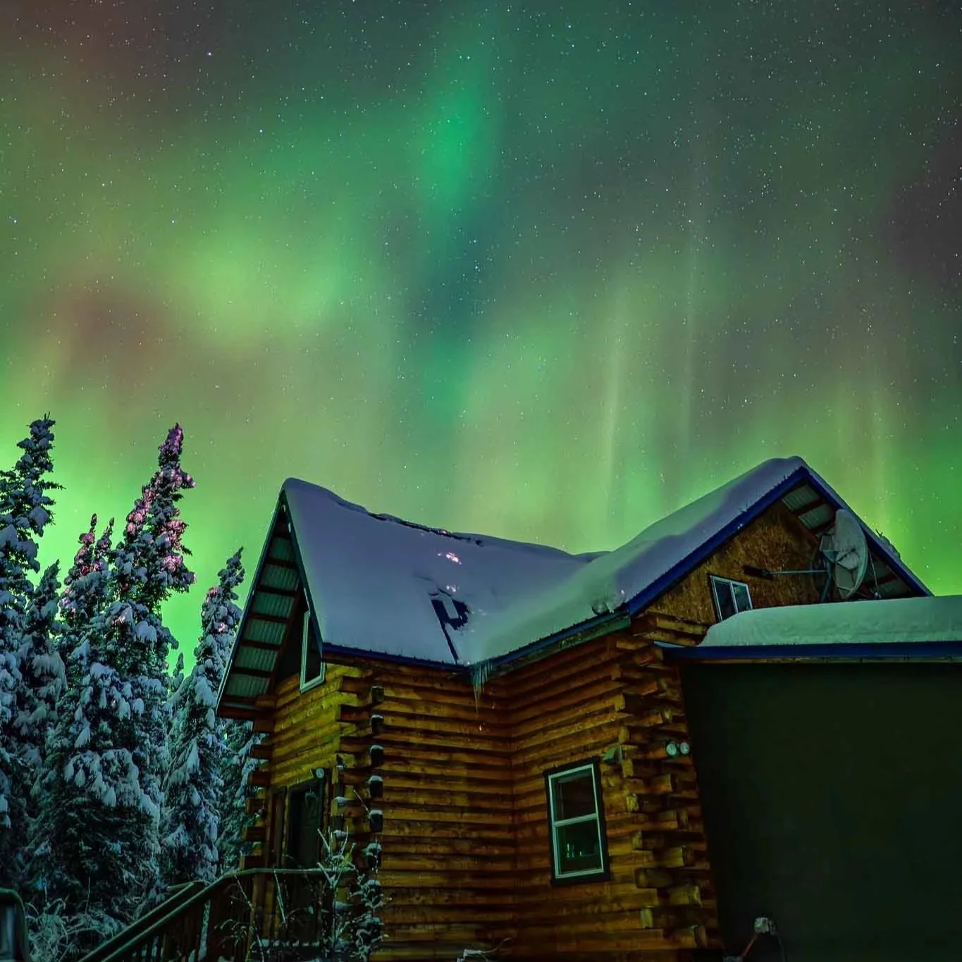  Cabin in the snow with the northern lights dancing in the sky. 