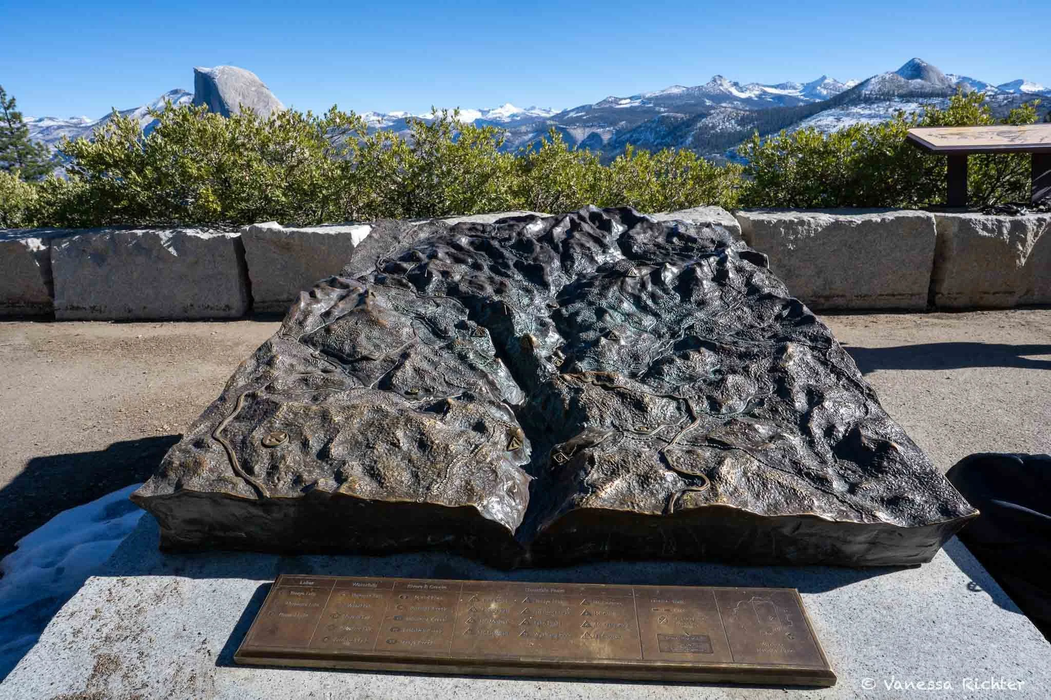 Display at Glacier Point informing visitors about which  geological features they're looking at. Half Dome and mountain panorama is visible in the background.