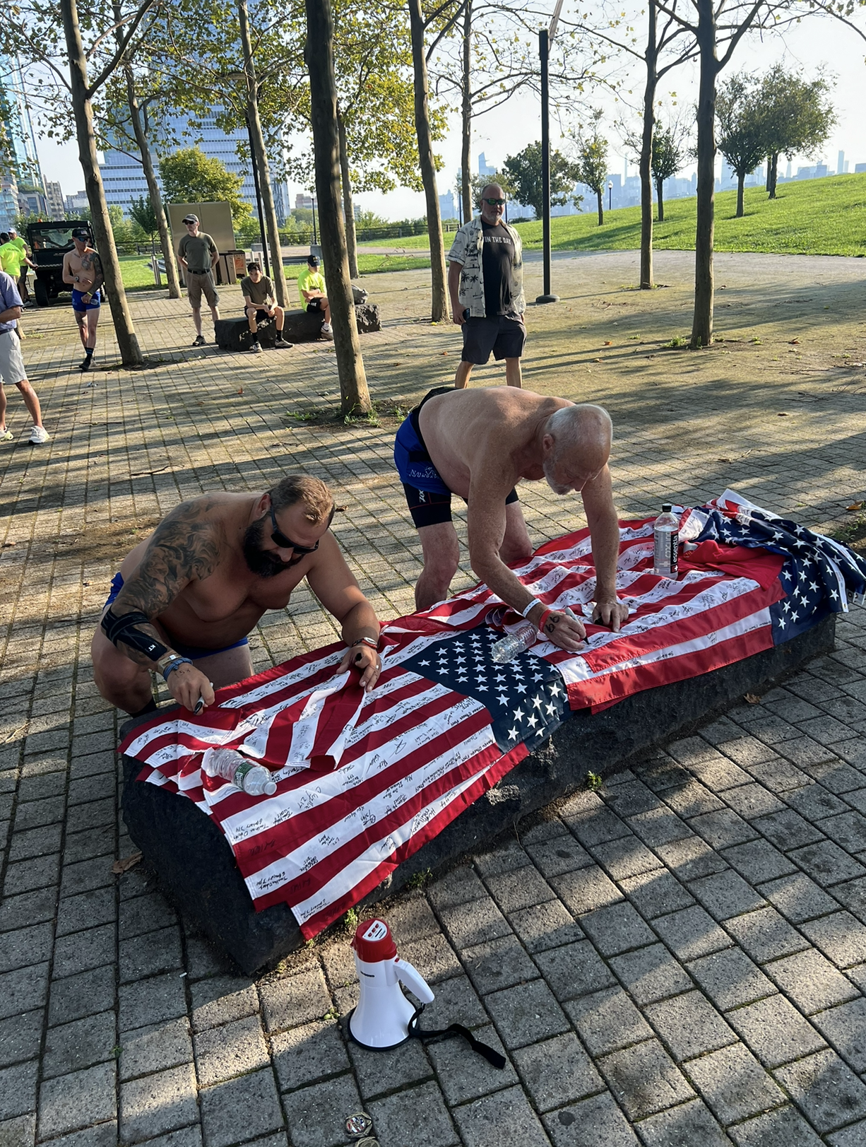 Two men signing an American Flag for the Navy Seal Foundation Fundraiser