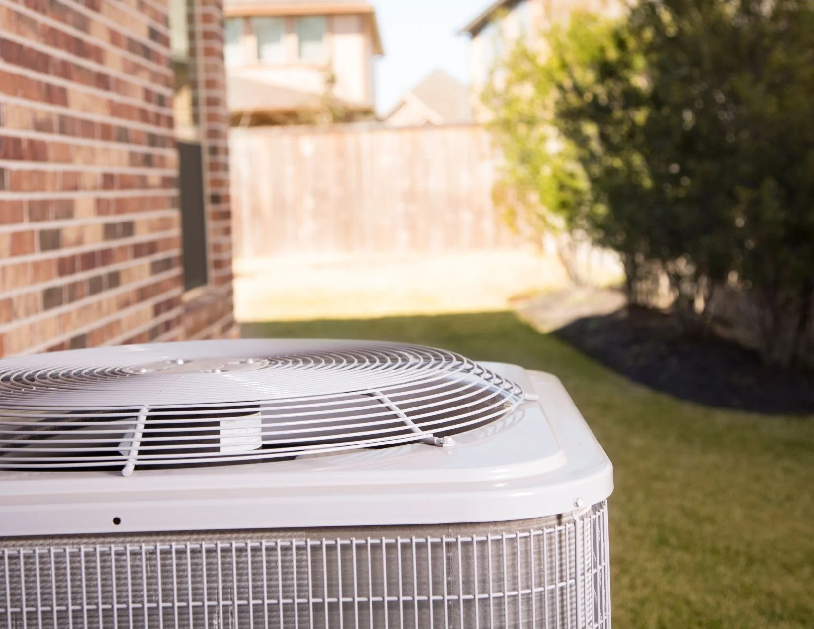 An air conditioning install in Edmonton Alberta stands in a yard on a sunny day