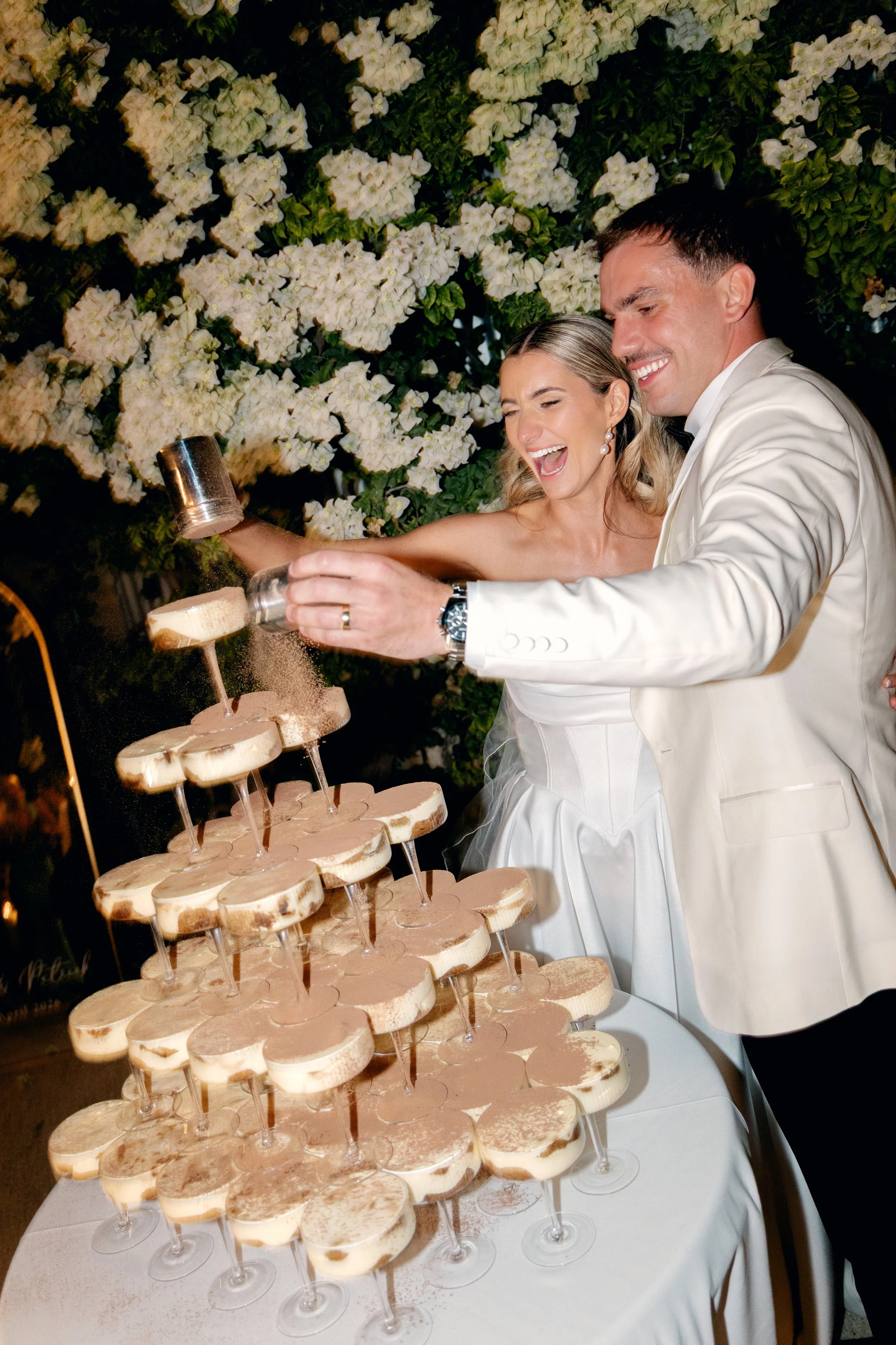 Bride and groom dusting cocoa powder over Tiramisu Tower at Perth wedding reception