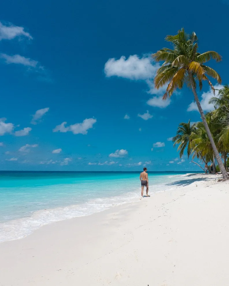 Someone walking along the white sandy shoreline by turquoise blue ocean