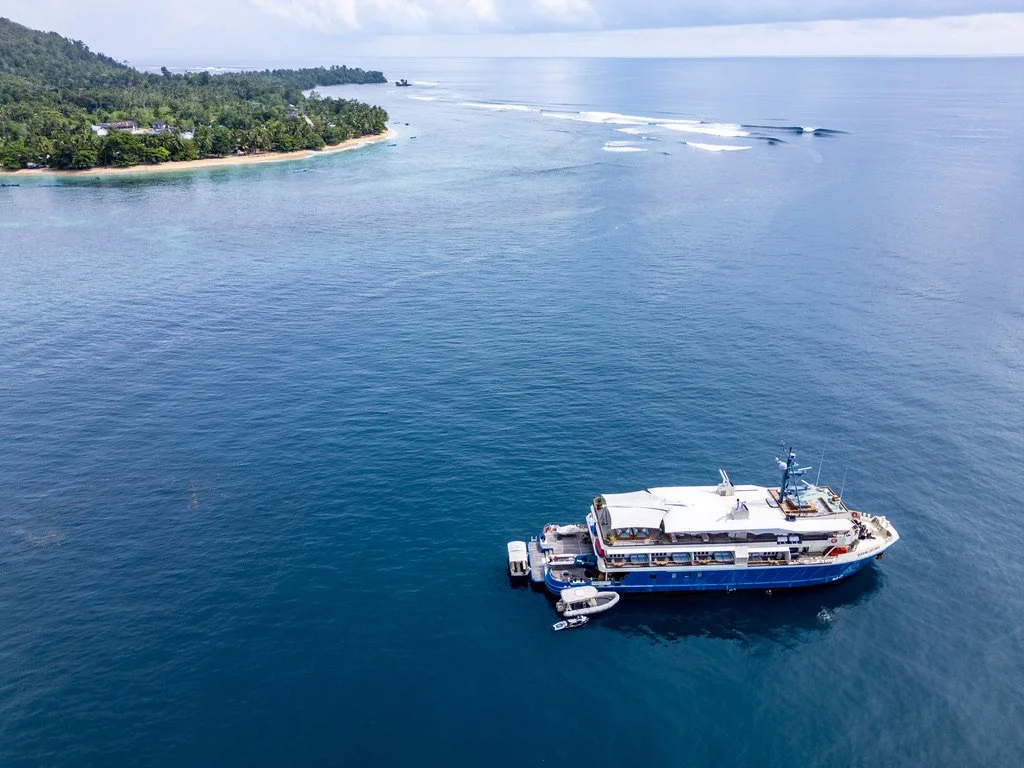 Aerial view of a luxury charter boat with breaking waves around the island