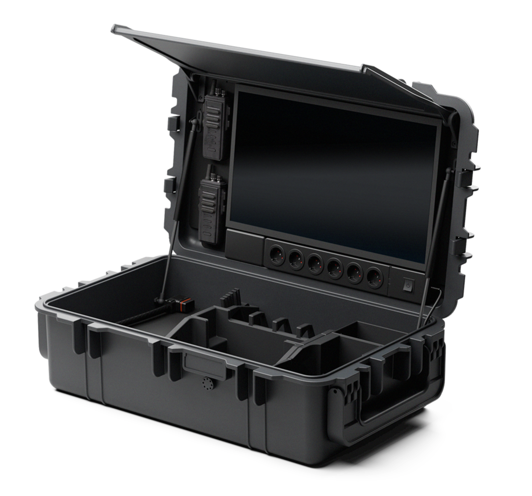 A rugged black carrying case with a flip-open lid displaying a large touchscreen monitor, various cables and sockets, and compartments inside.