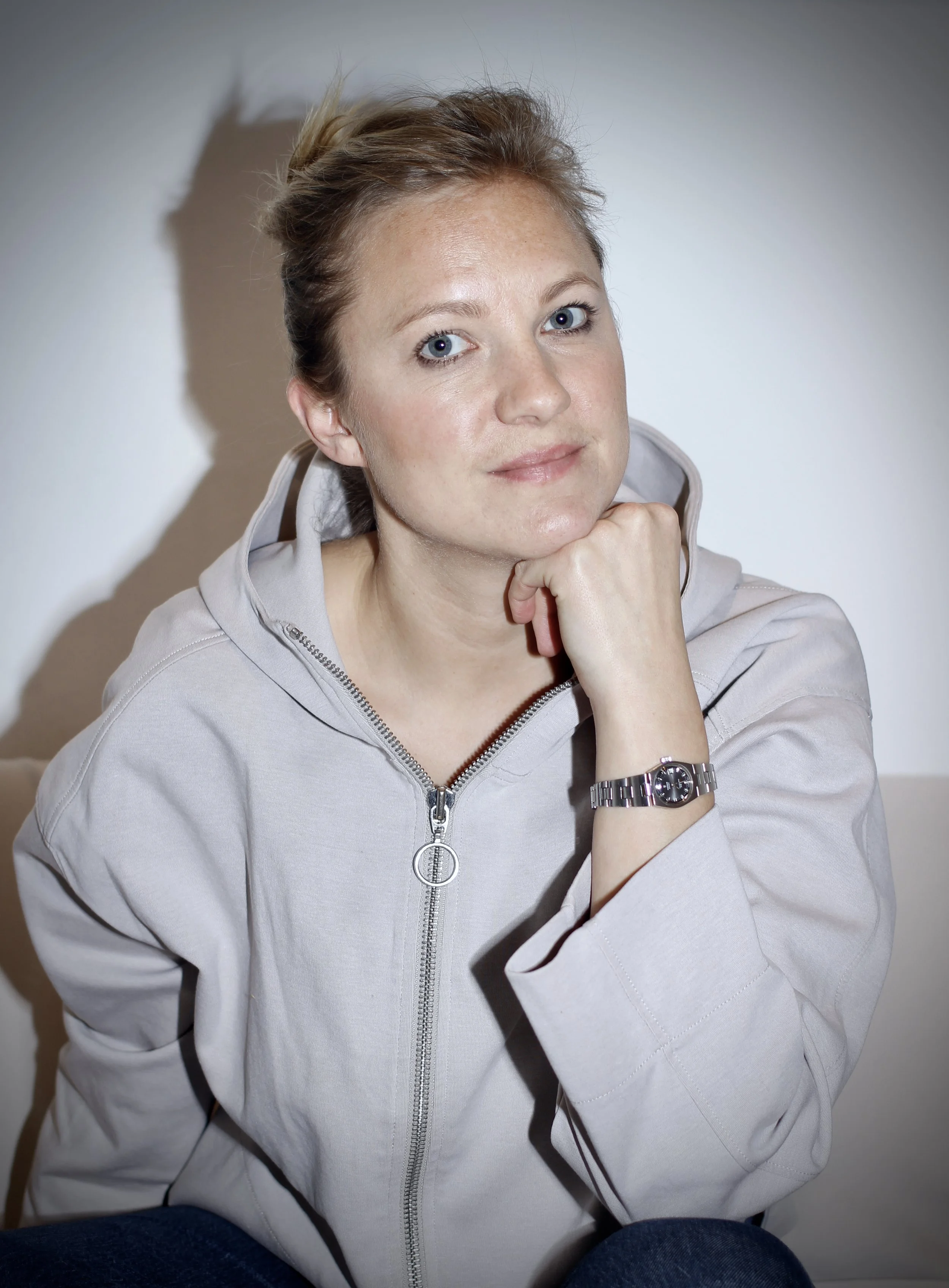 Schwarz-Weiß-Foto einer lachenden  attraktiven Gründerin mit langen Haaren, die einen schwarzen Pulli trägt, vor neutralem Hintergrund.