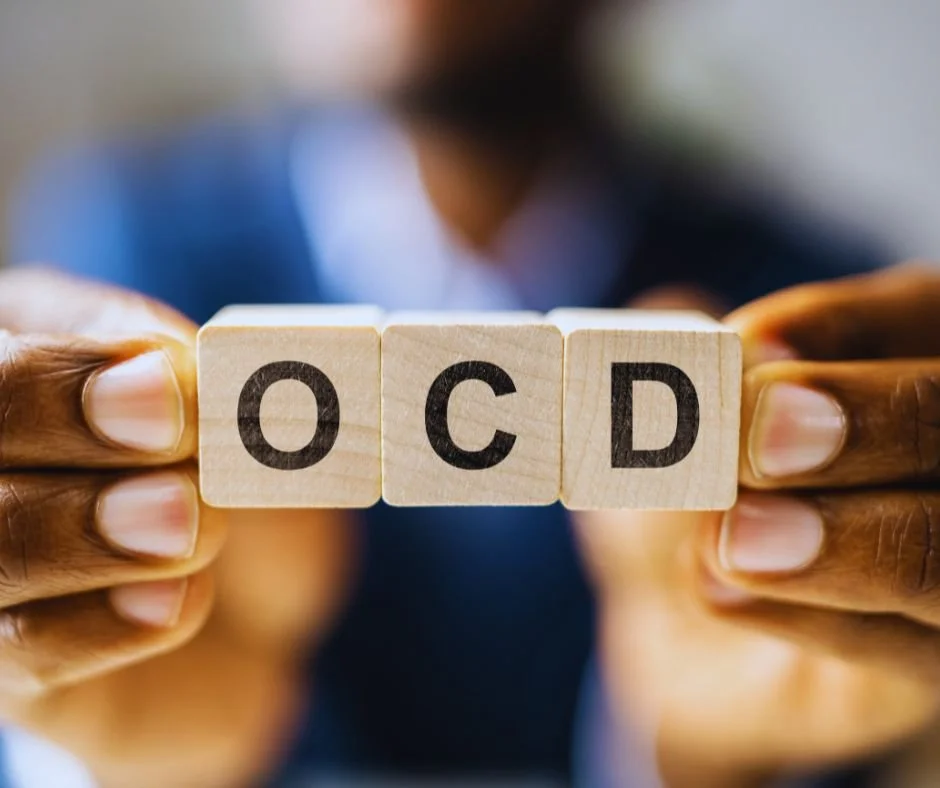 Person holding wooden blocks with the letters 'OCD' written on them.