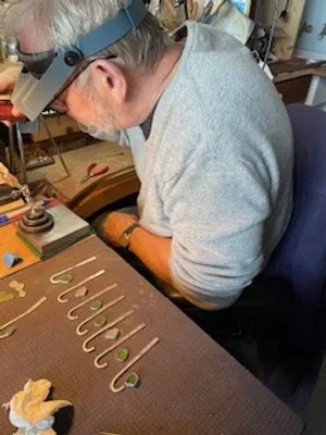 A person working at a workbench with hooks and tools, wearing a headlamp and gray shirt.