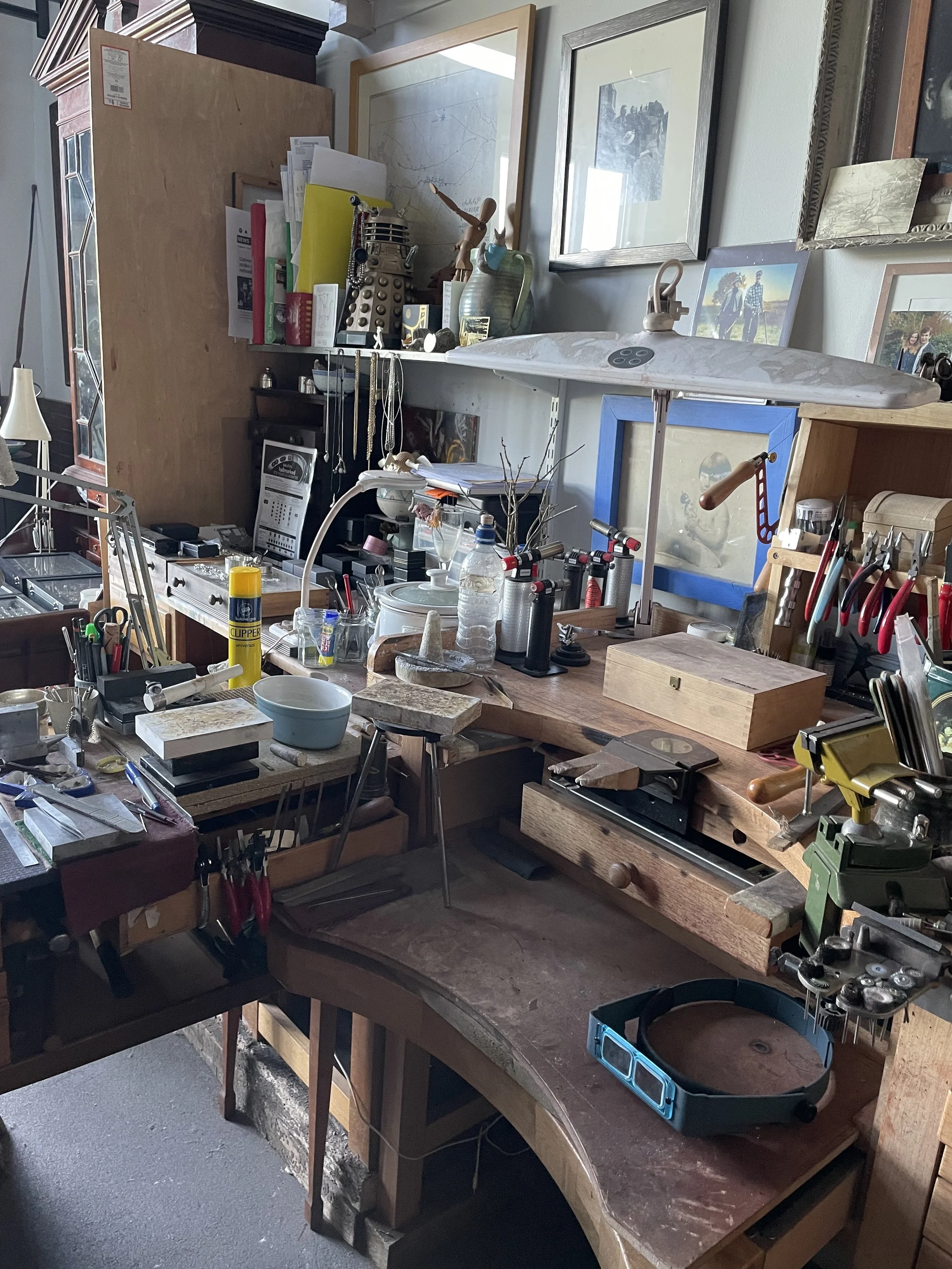 A woodworking workbench with tools, supplies, and framed pictures on the wall above.
