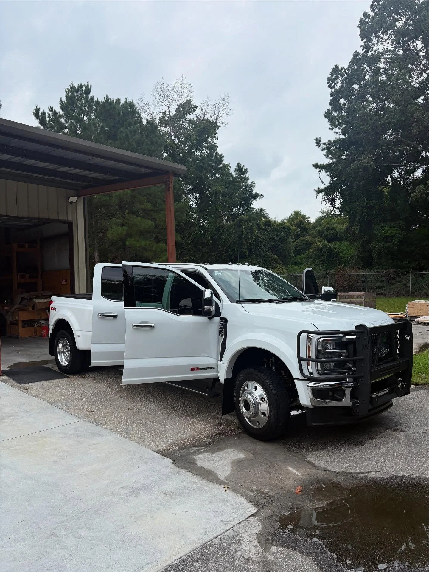 white f450 parked Infront of a warehouse with all doors open