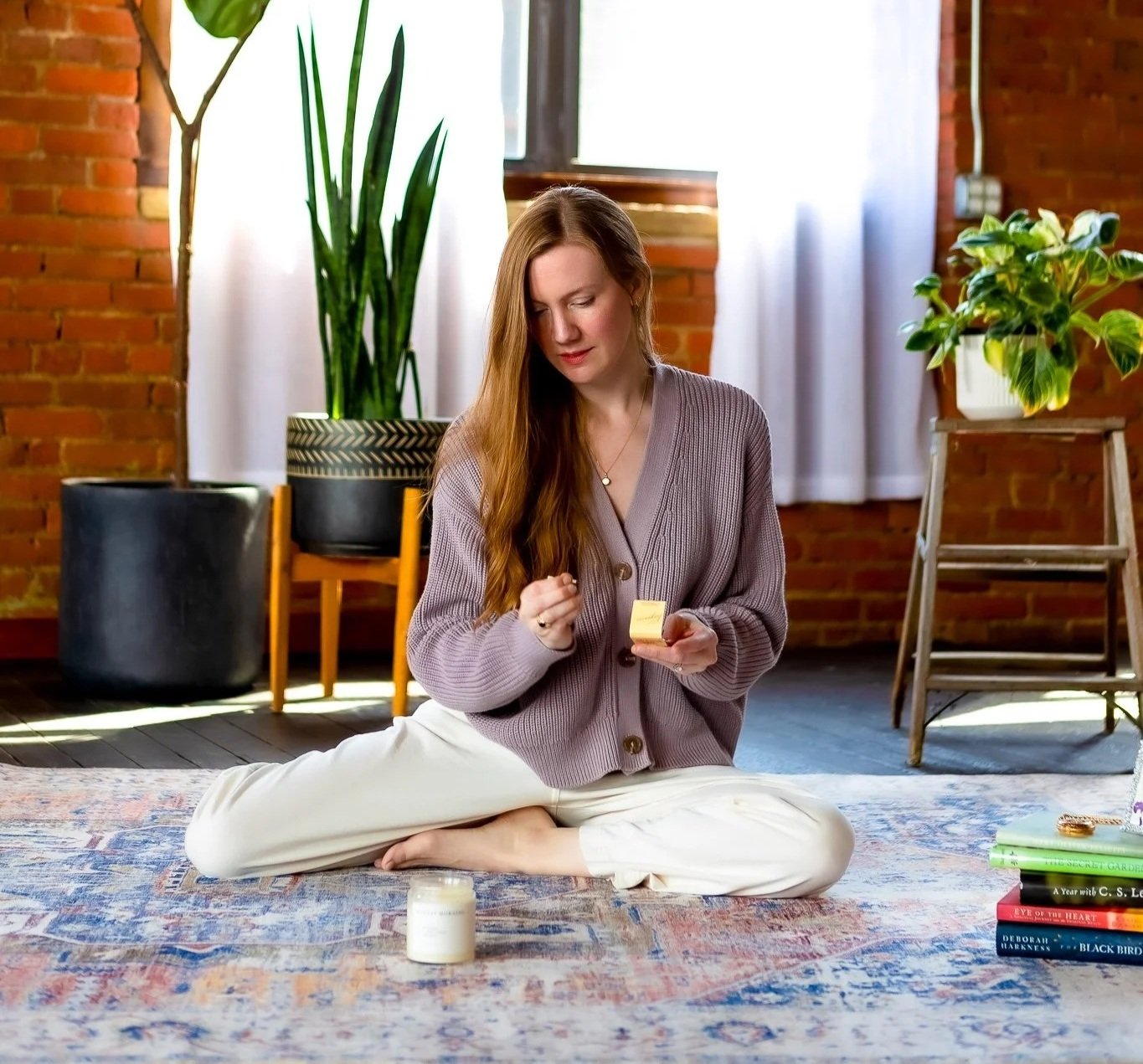 Woman with long red hair sits on the floor, holding a match that she's about to light