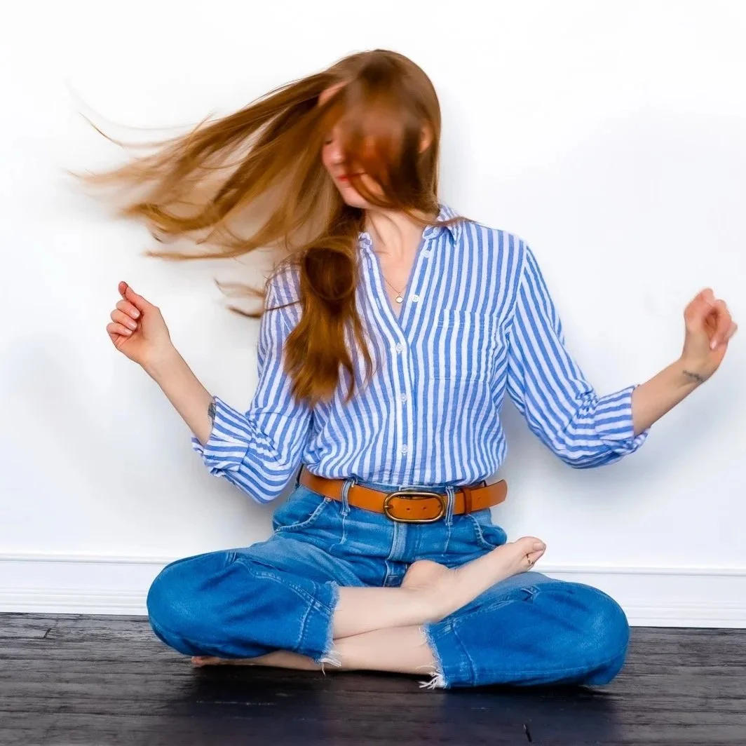 Virginia sitting cross legged and dancing in her seat, red hair blowing in the wind