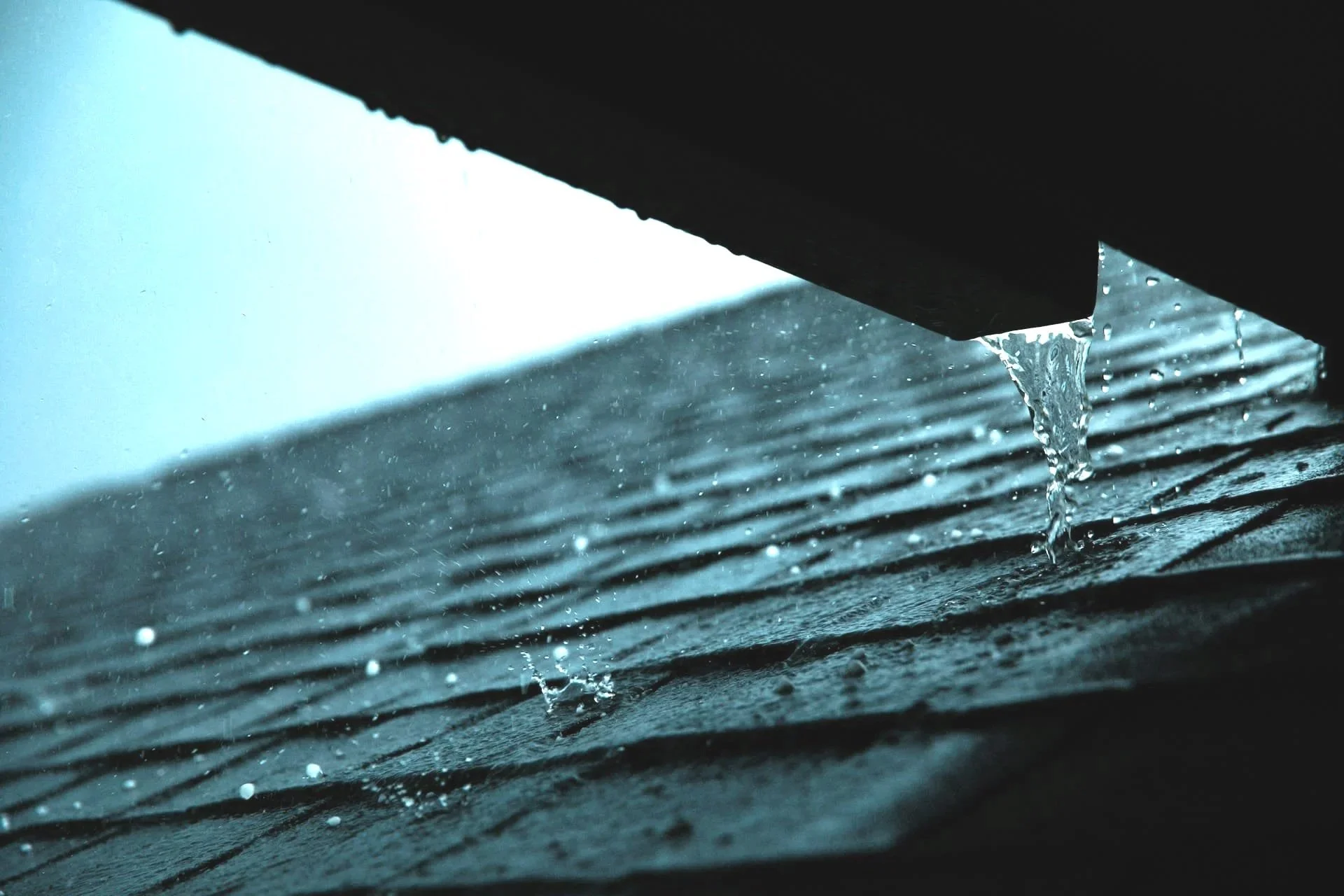 Rainwater draining from asphalt shingle roof on a Calgary home, illustrating roof repair and leak prevention