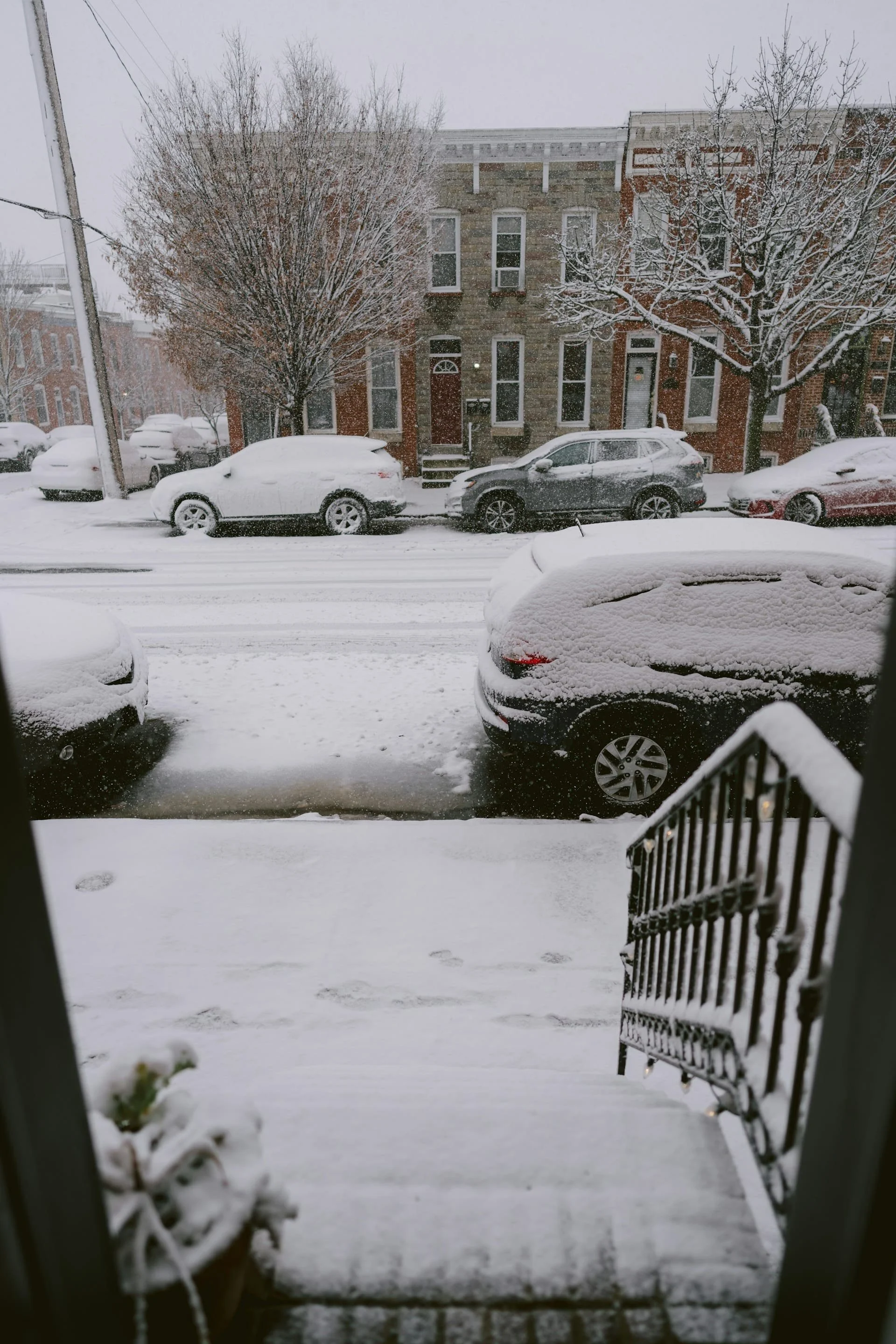 Residential street in Calgary covered in fresh snowfall with snow-covered cars, driveway, and sidewalk