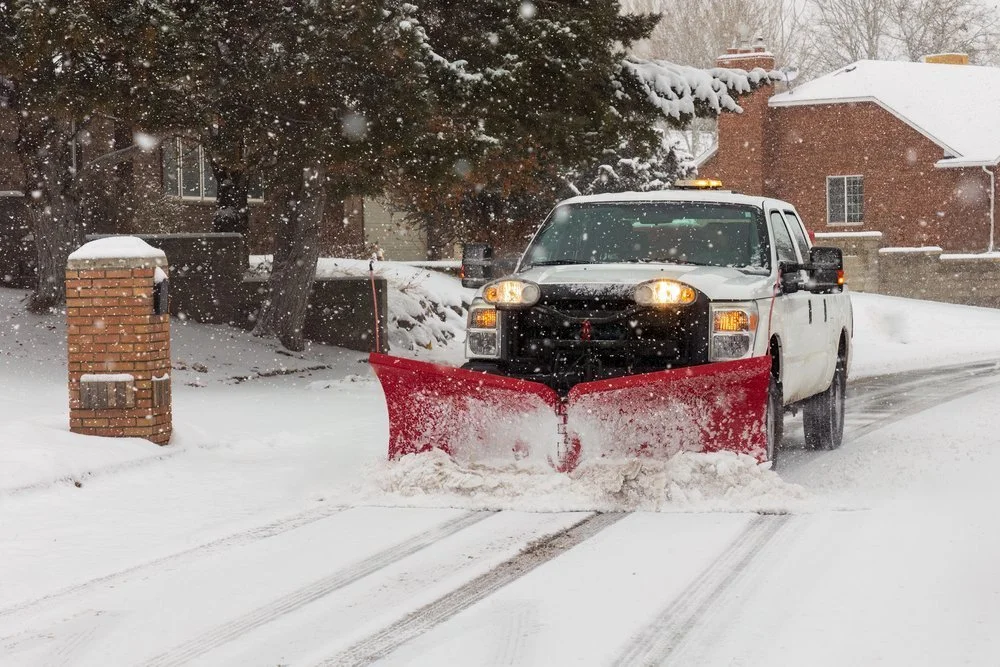 Snow plow truck clearing snow in Calgary during active snowfall for commercial snow removal