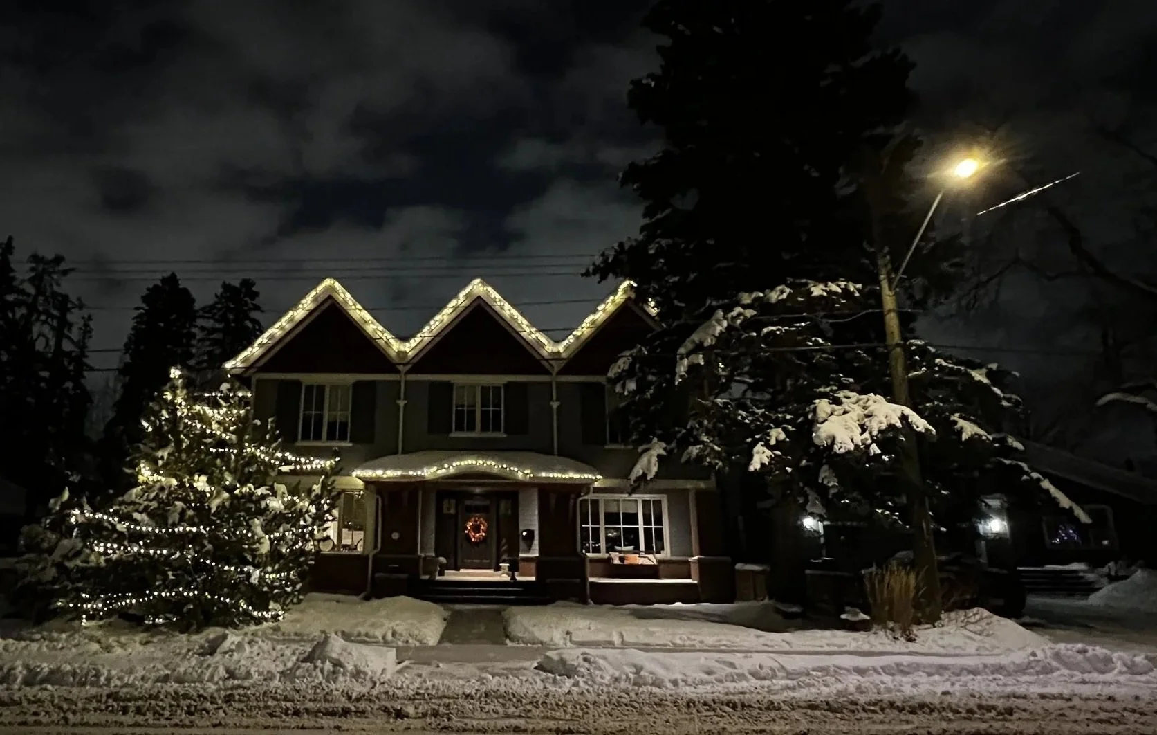 C6 warm white Christmas lights double wrapped on residential roofline and tree in Calgary by a professional lighting company