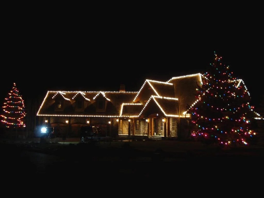 Professional residential Christmas light installation in Calgary with C9 warm white roofline lights and C6 multi-colour lights on trees