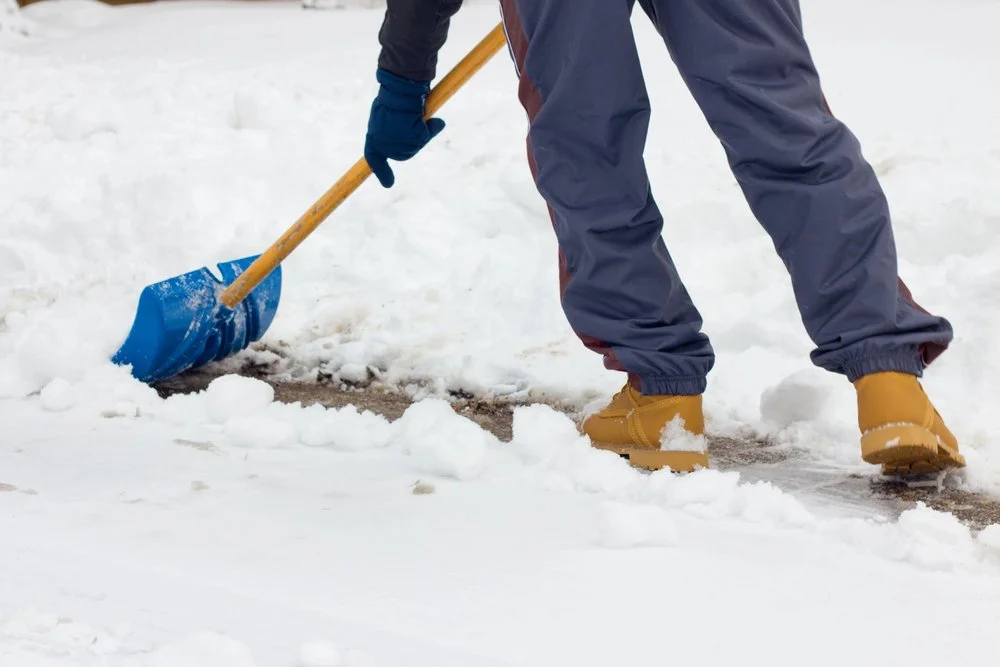 Person shoveling snow off a sidewalk in Calgary during winter for residential snow removal