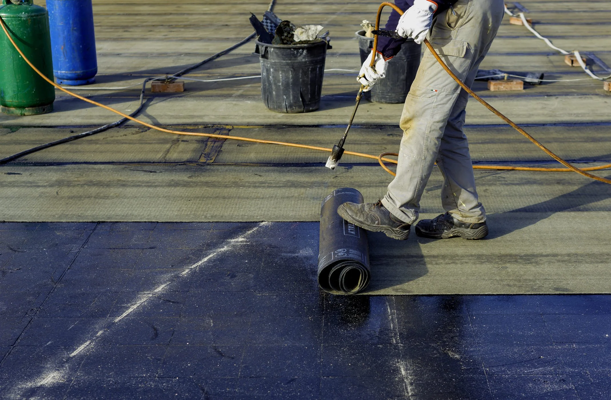 Worker installing torch-on bitumen membrane on a commercial flat roof