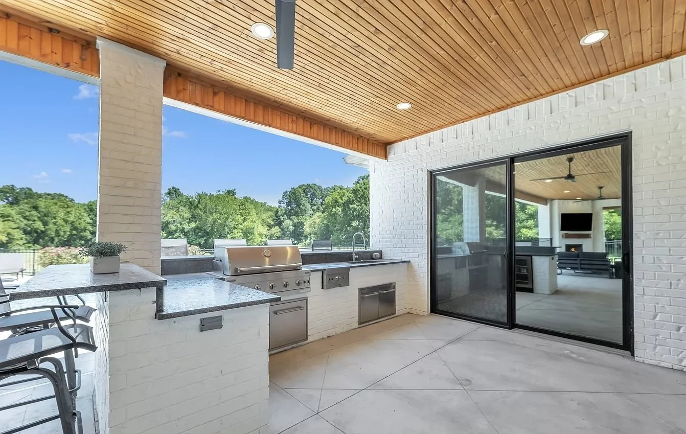 Outdoor kitchen with stainless grill under a cedar-clad covered patio in Fulshear, TX