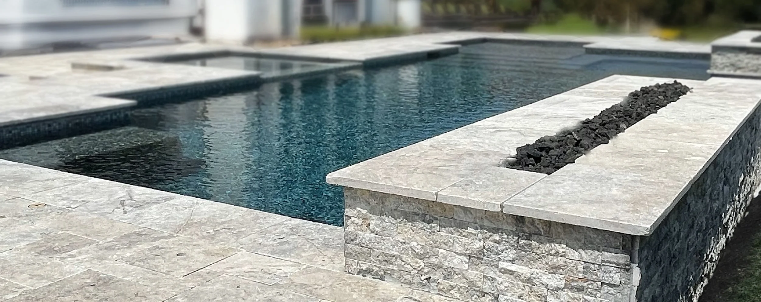 Custom pool in Bridgeland with silver travertine decking and linear firepit