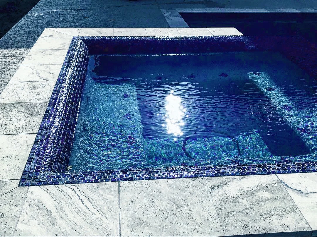 Custom rolled neck spa in Elyson with silver travertine coping in Katy, Tx