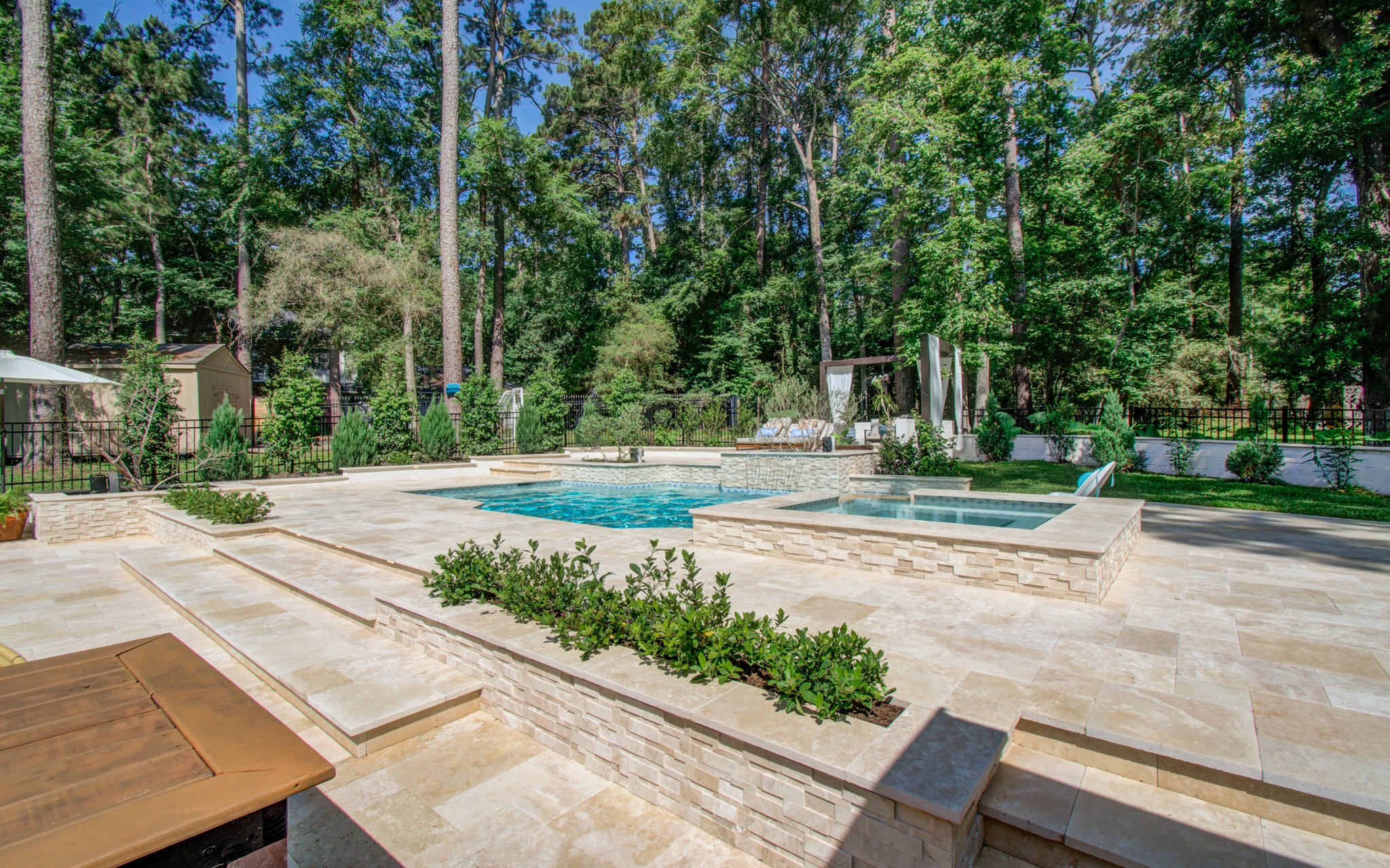 Covered patio and travertine dining terrace beside a 32-foot geometric pool
