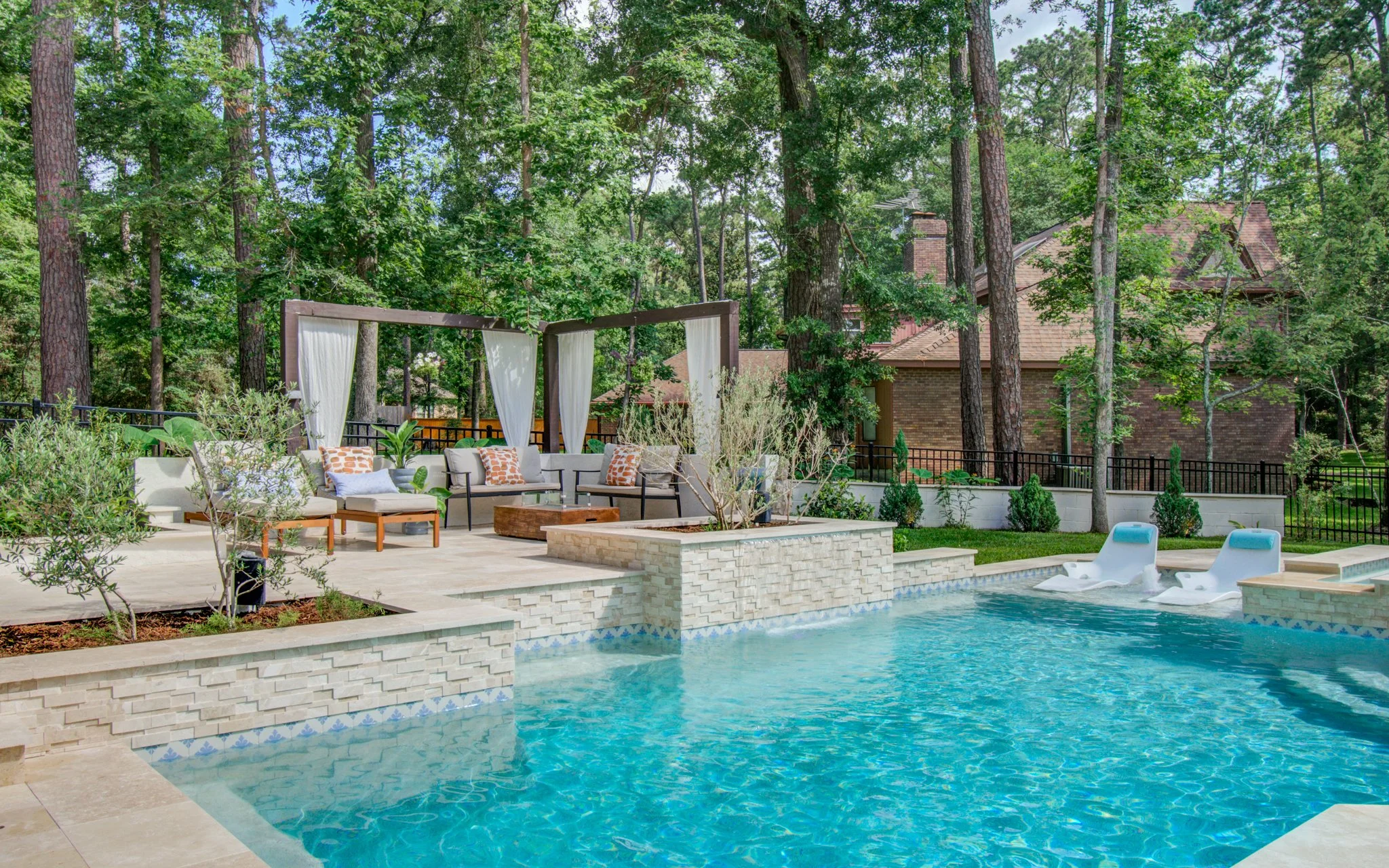 Curtained cedar cabana pergola and lounge seating at the tree line