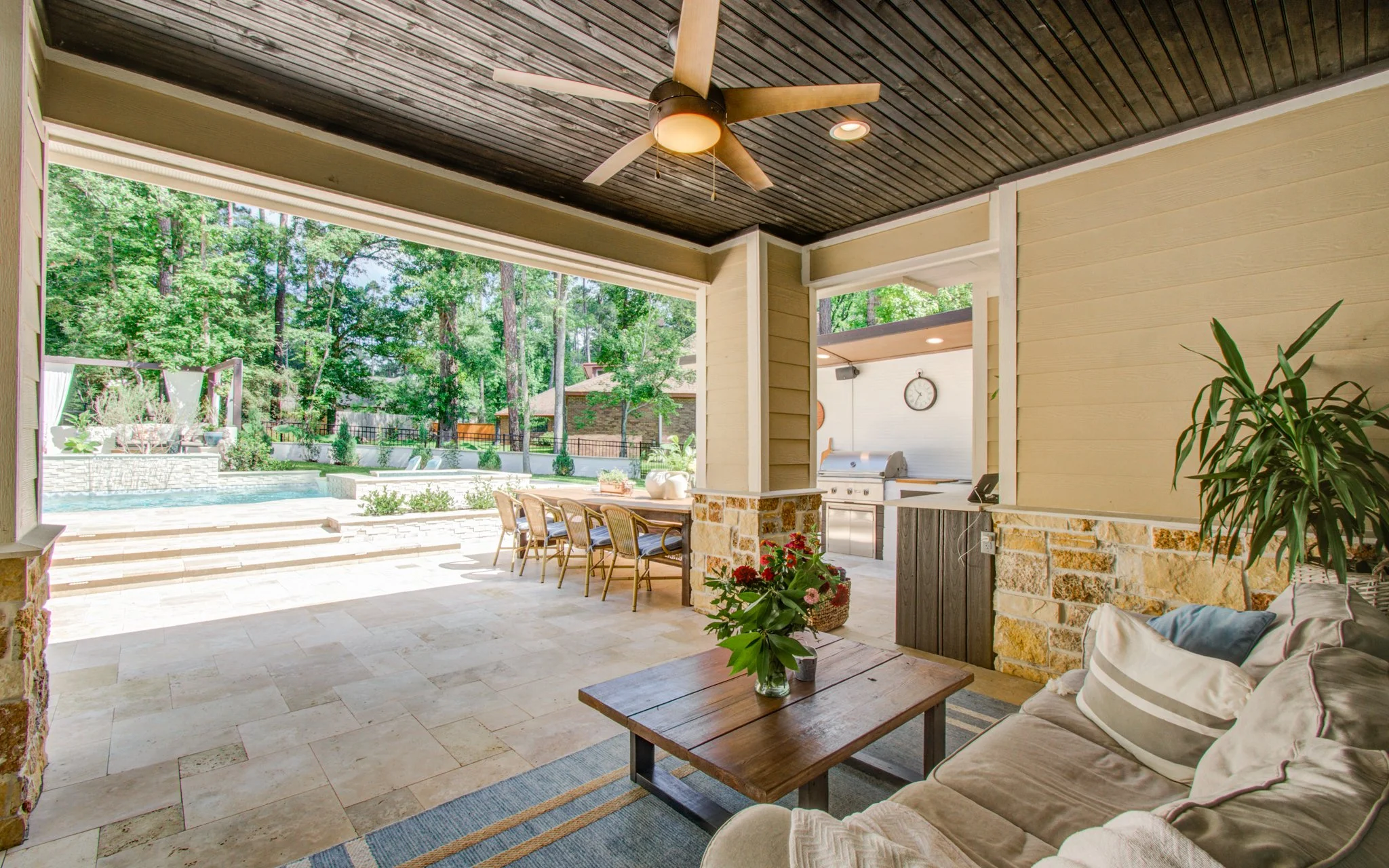 Covered patio and travertine dining terrace beside a 32-foot geometric pool