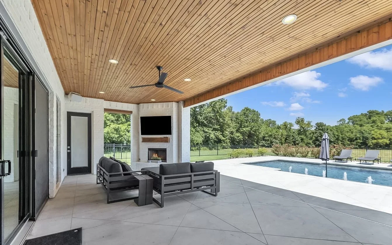 Outdoor kitchen with stainless grill under a cedar-clad covered patio in Fulshear, TX