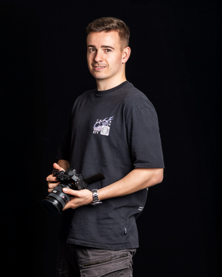 Einer der drei Gründer Daniel Leichtfried hält eine Kamera vor einem schwarzen Hintergrund.