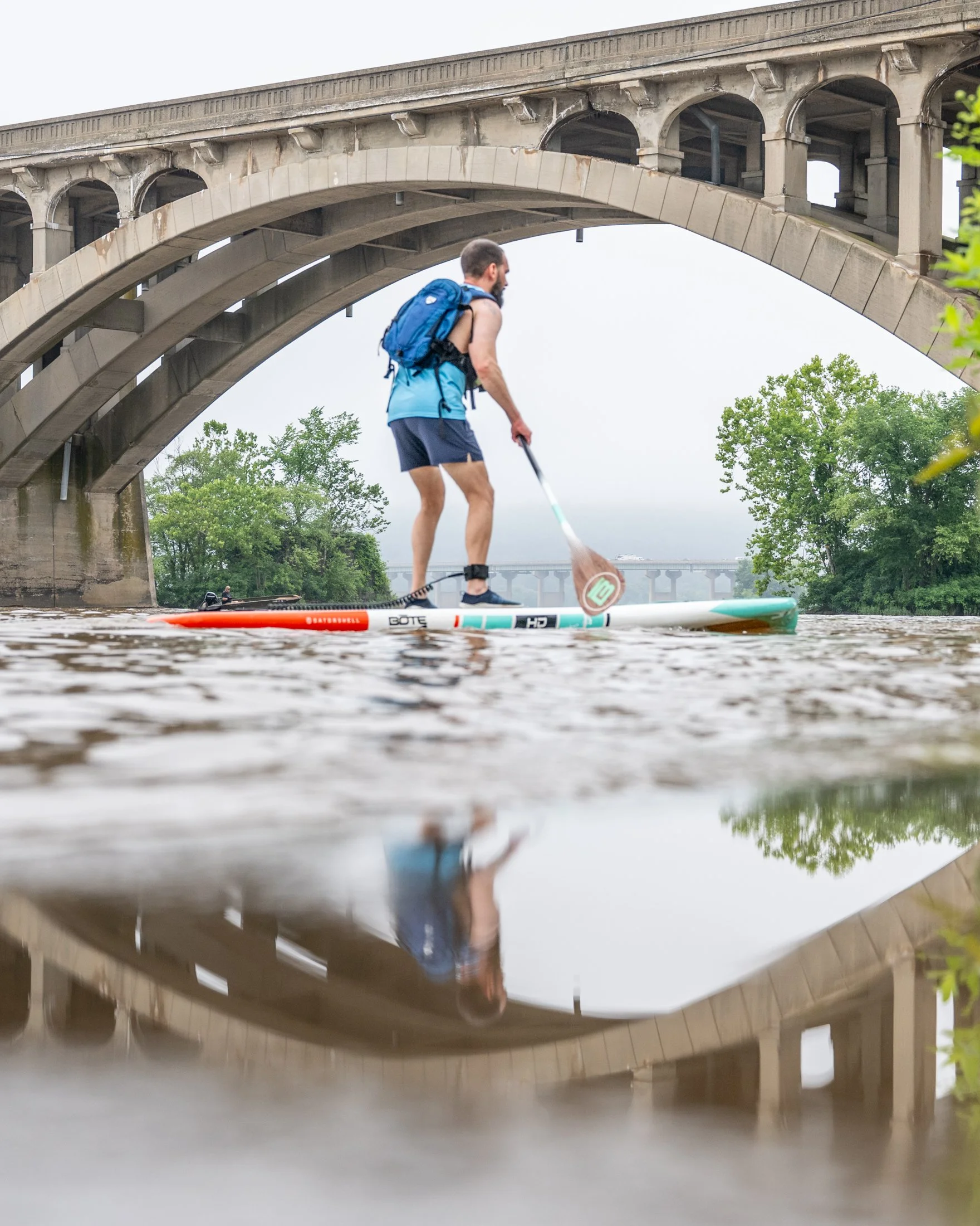 A competitor in the Bridge Burner Challenge completes a paddle board crossing on the Susquehanna River.