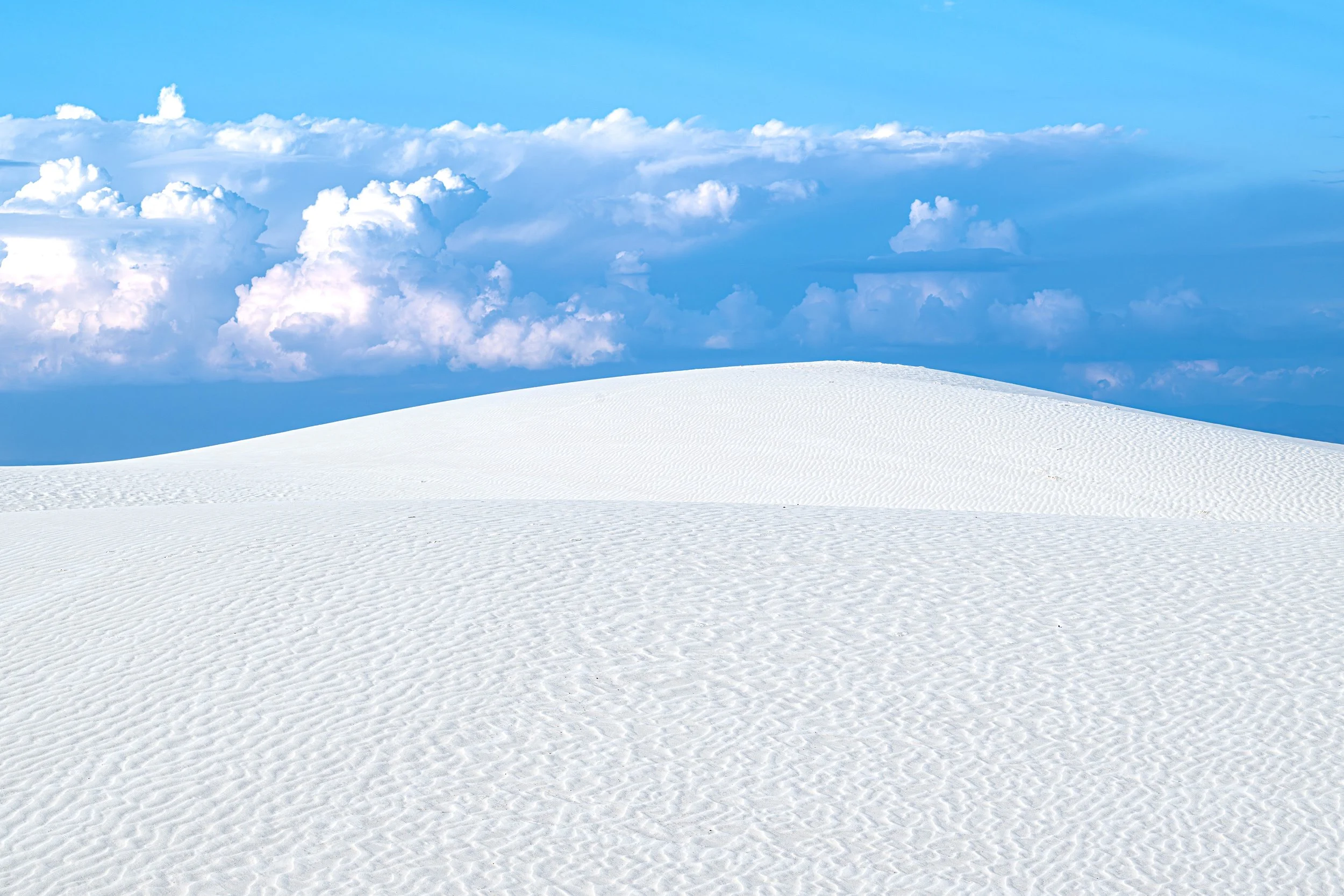 White Sands National Park textured gypsum dune set against a sapphire blue sky