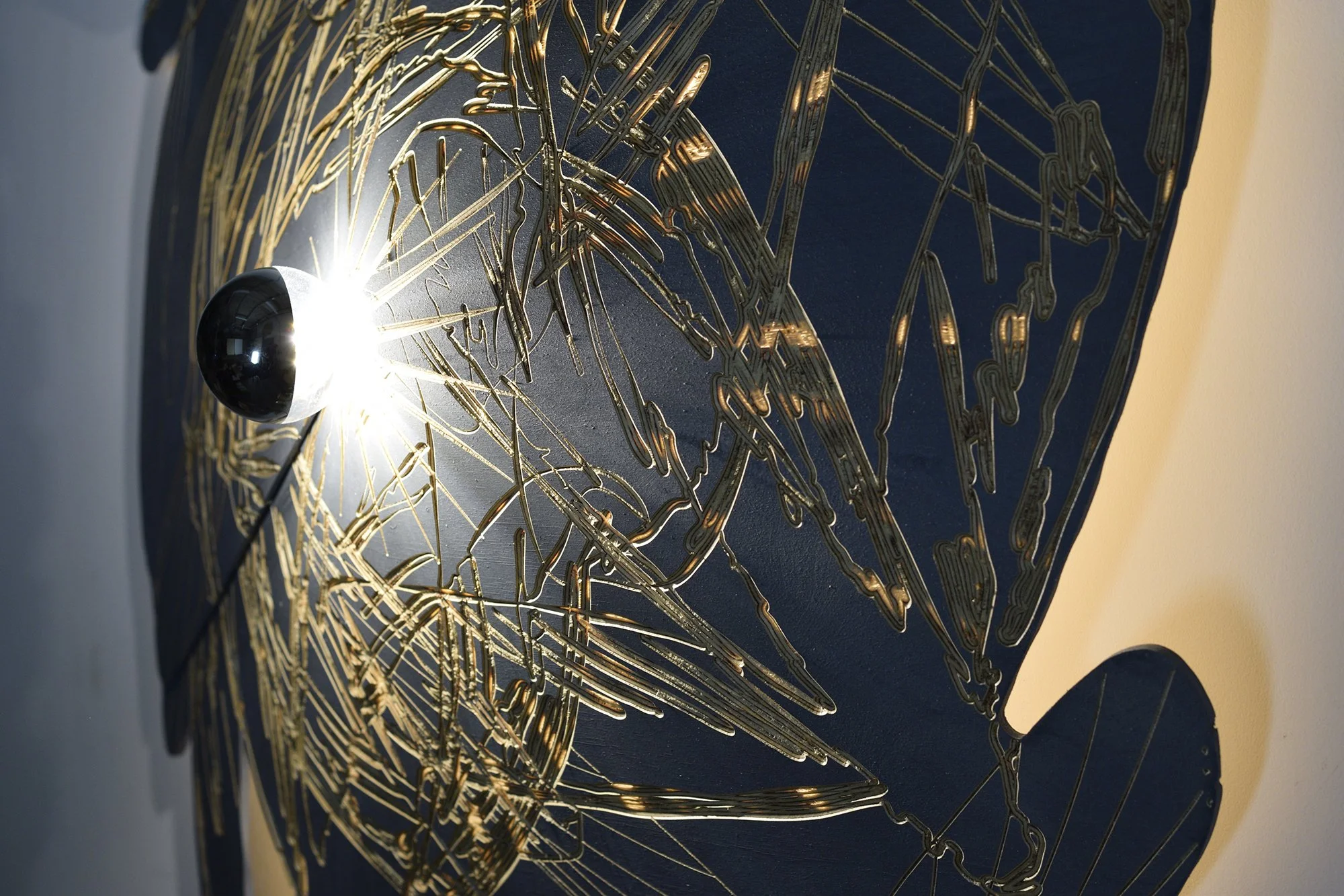 Insect patterns are carved on the front and rear of a piece of bent plywood. Light shines through the negative space created where the patterns intersect.