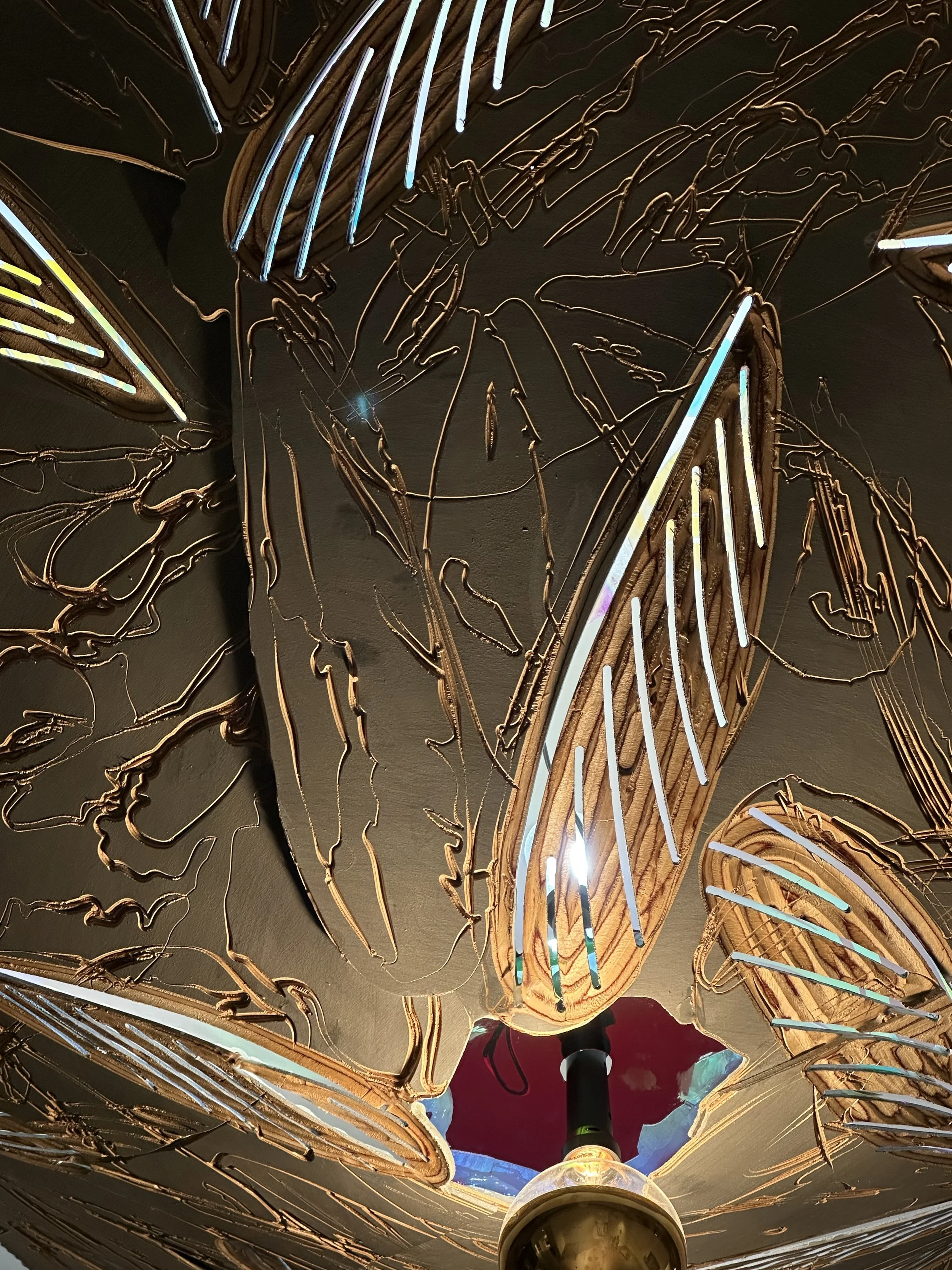 Termite wings and markings are carved into the wooden shade, the surface pierced by the iridescent sheen of termite wings.