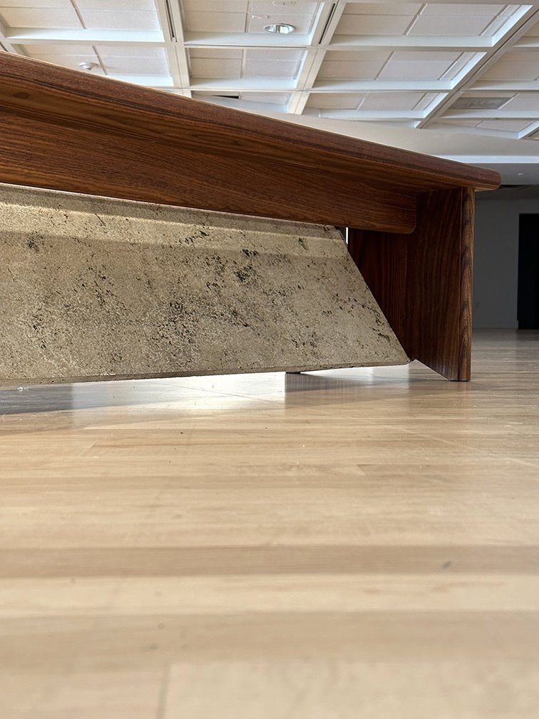 Drip detail. As the ash wood ages from dark brown to silver grey, the embedded copper plates slowly patina, dripping green oxidation onto the porous travertine.