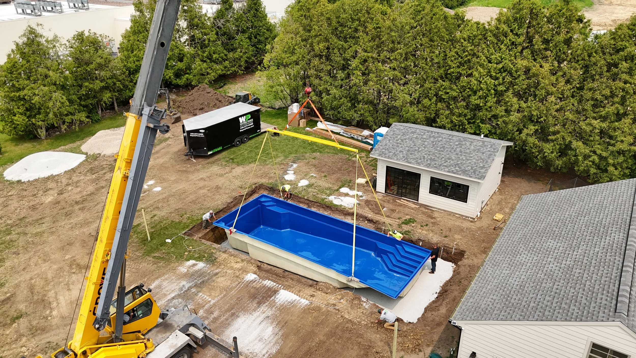 Wapsie Pines employees crane fiberglass pool into hole.