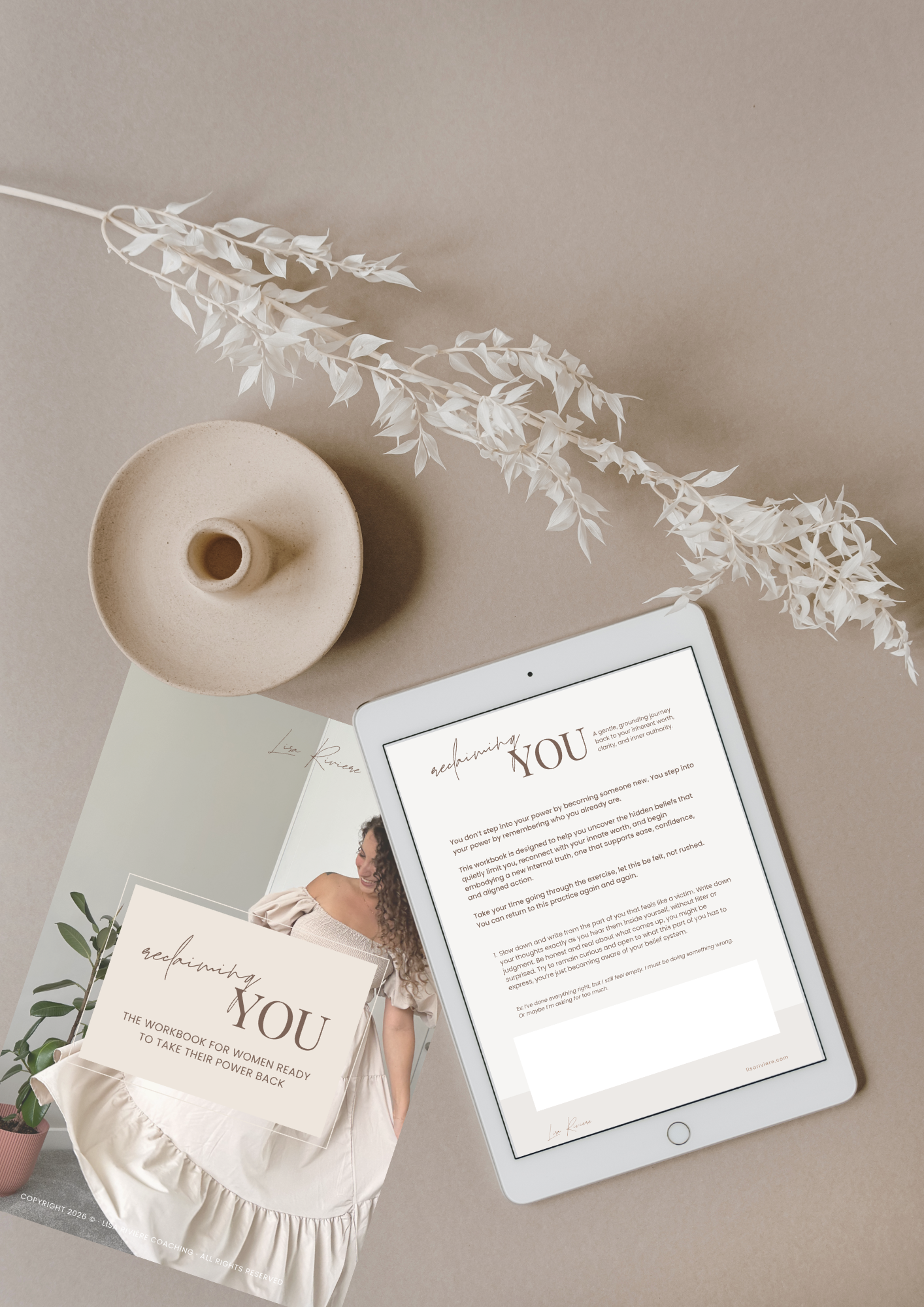 A tablet displaying a coaching workbook titled 'Reclaiming YOU' on a beige background with a white vase holding a white decorative branch, a white booklet, and a partially visible pink pot with a green plant.