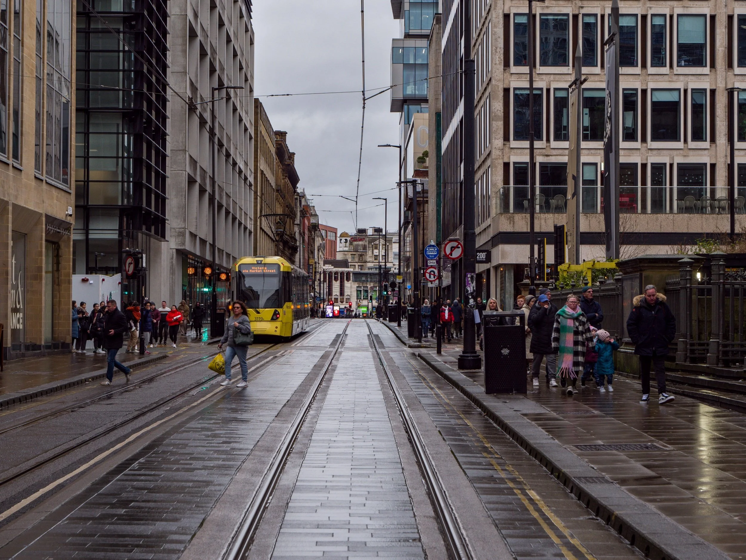 Urban street scene with tram and pedestrians on a rainy day in a city