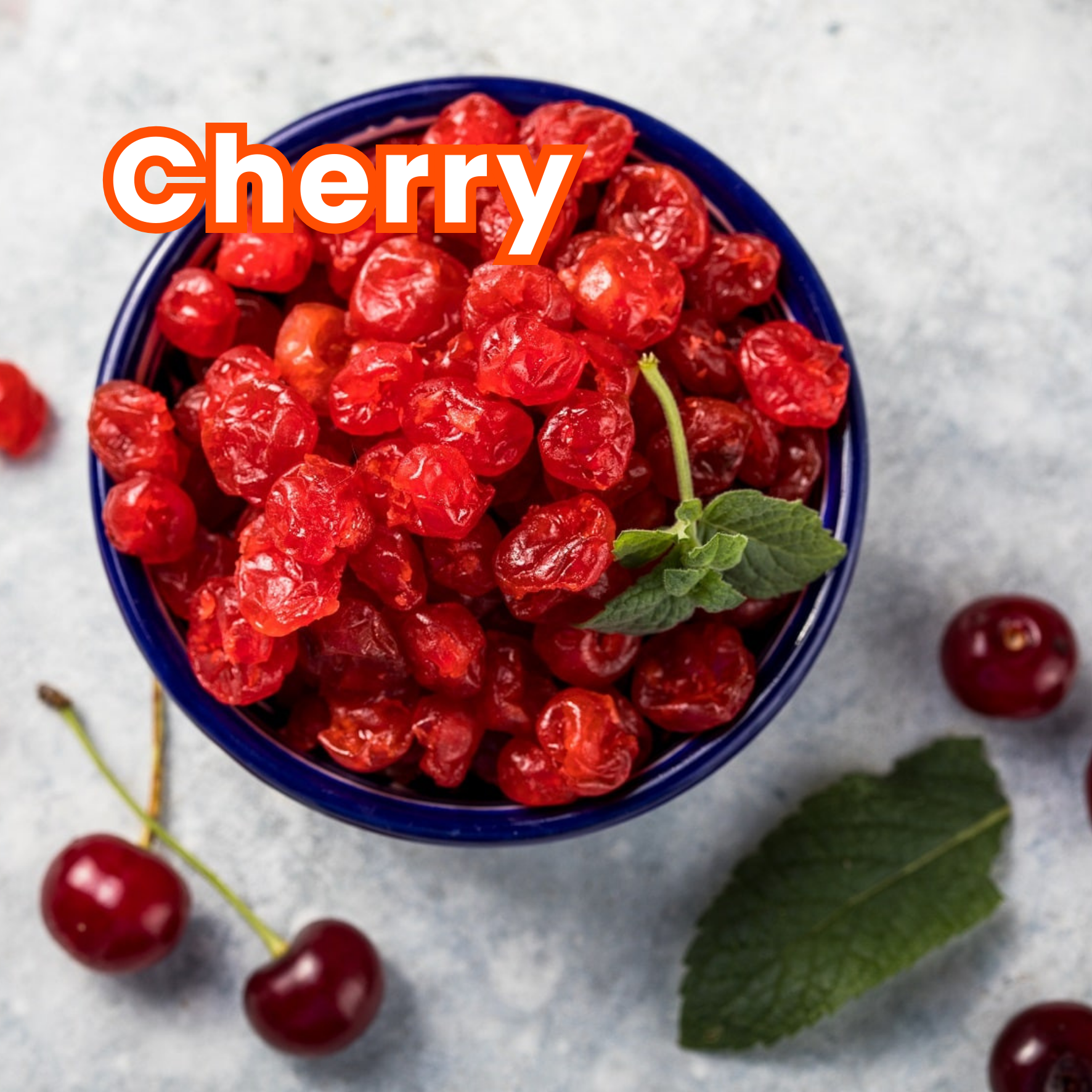 A blue bowl filled with red cherry berries garnished with a green mint leaf, placed on a gray surface with a few cherries and a leaf scattered around.