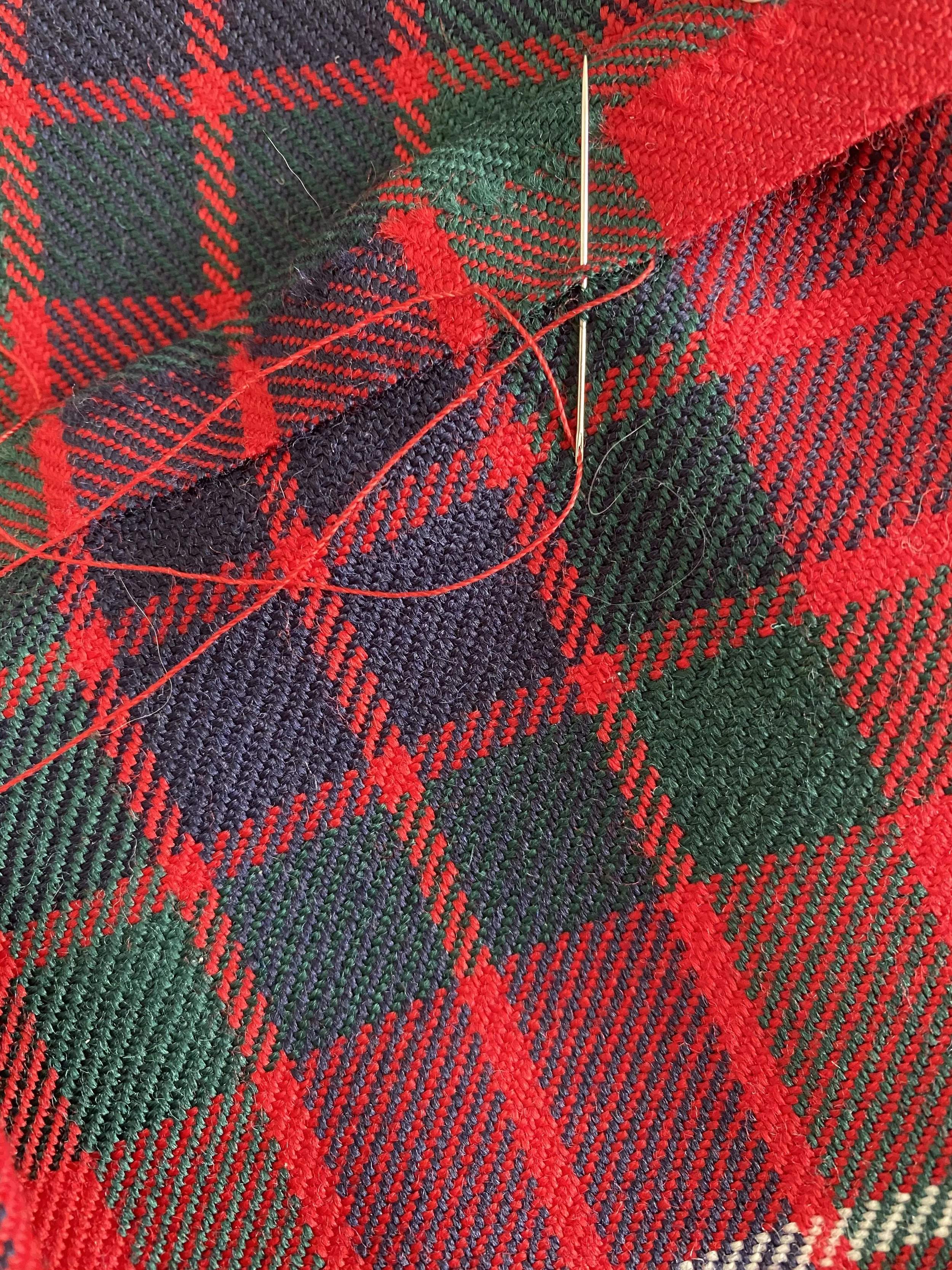 Close-up of Fraser of Lovat tartan with sewing needle and thread.