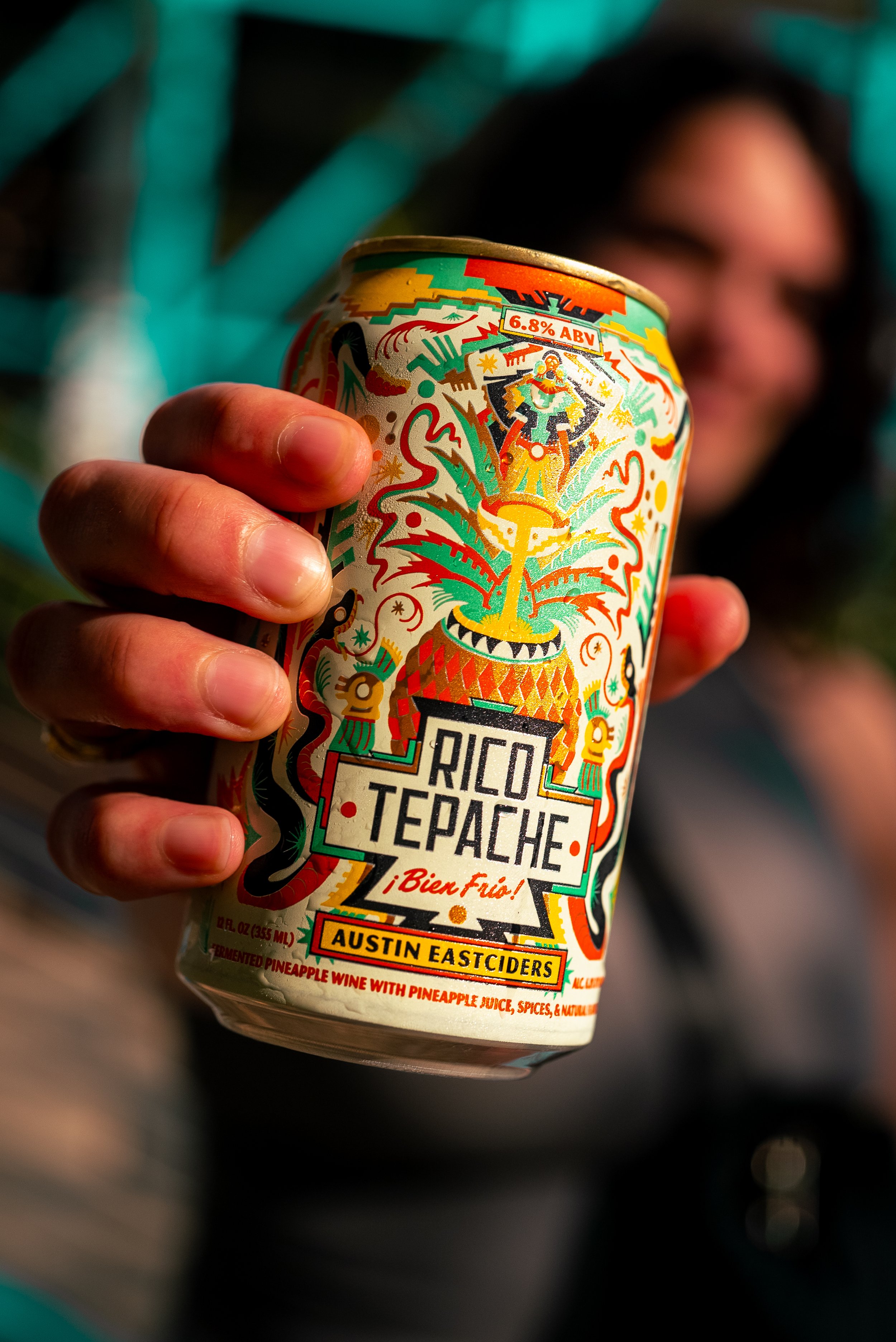 Commercial beverage and food product photography of a woman in her late 20s holding a Rico Tepache Austin Eastciders pineapple beverage, featuring vibrant color and shallow depth of field with a blurred background, creating an eye-catching, lifestyle