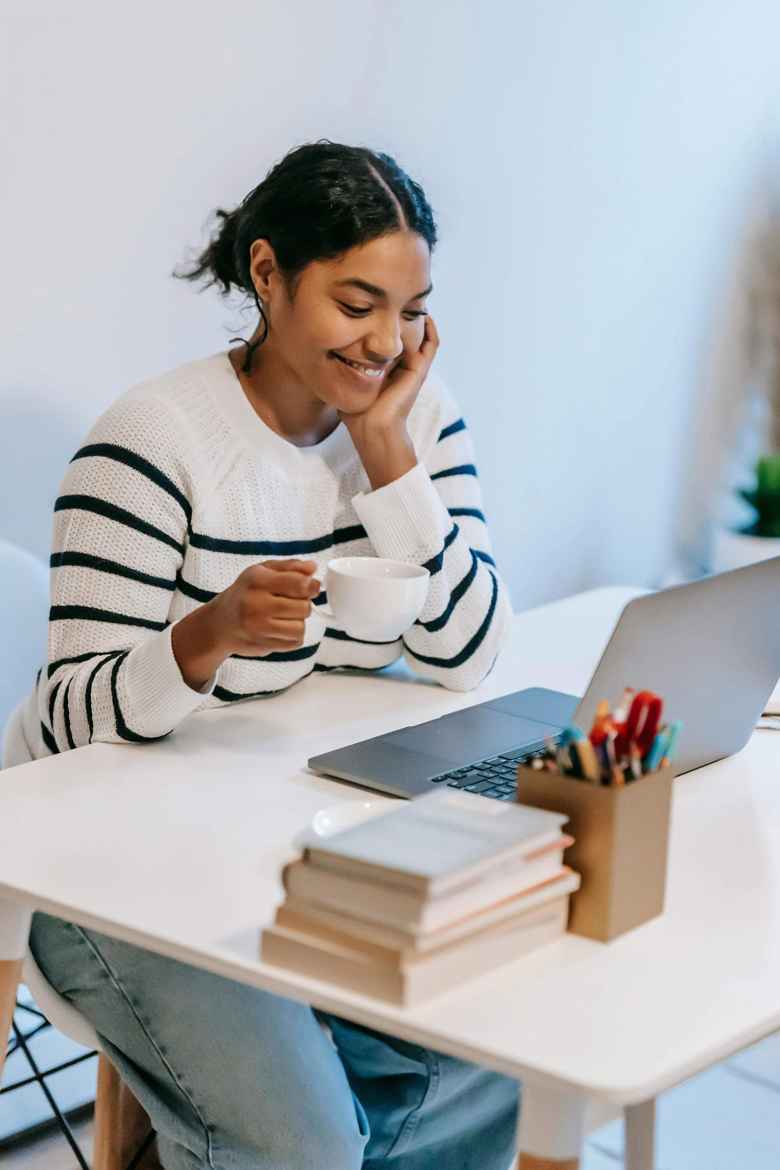 Therapist sitting at a computer holding a mug and smiling, representing a calm and approachable approach to SEO for private practice