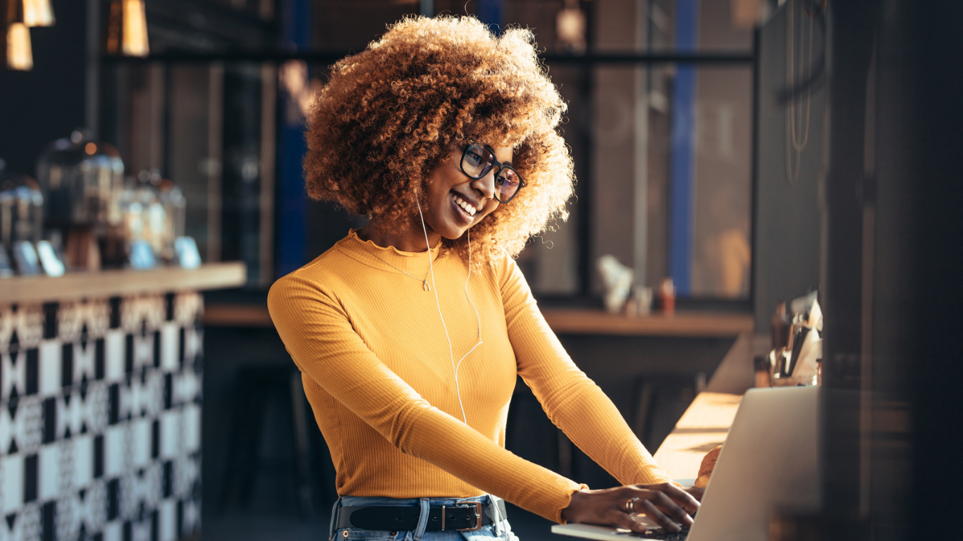 Therapist smiling while working on a laptop, reflecting confidence and ease gained through ongoing marketing support