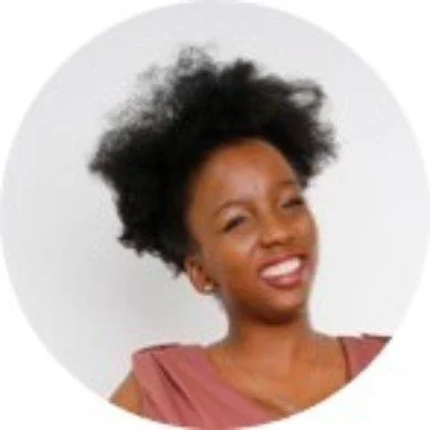 Jeune femme afro-américaine souriante avec cheveux afro bouclés, portant un haut rose, contre un fond blanc.