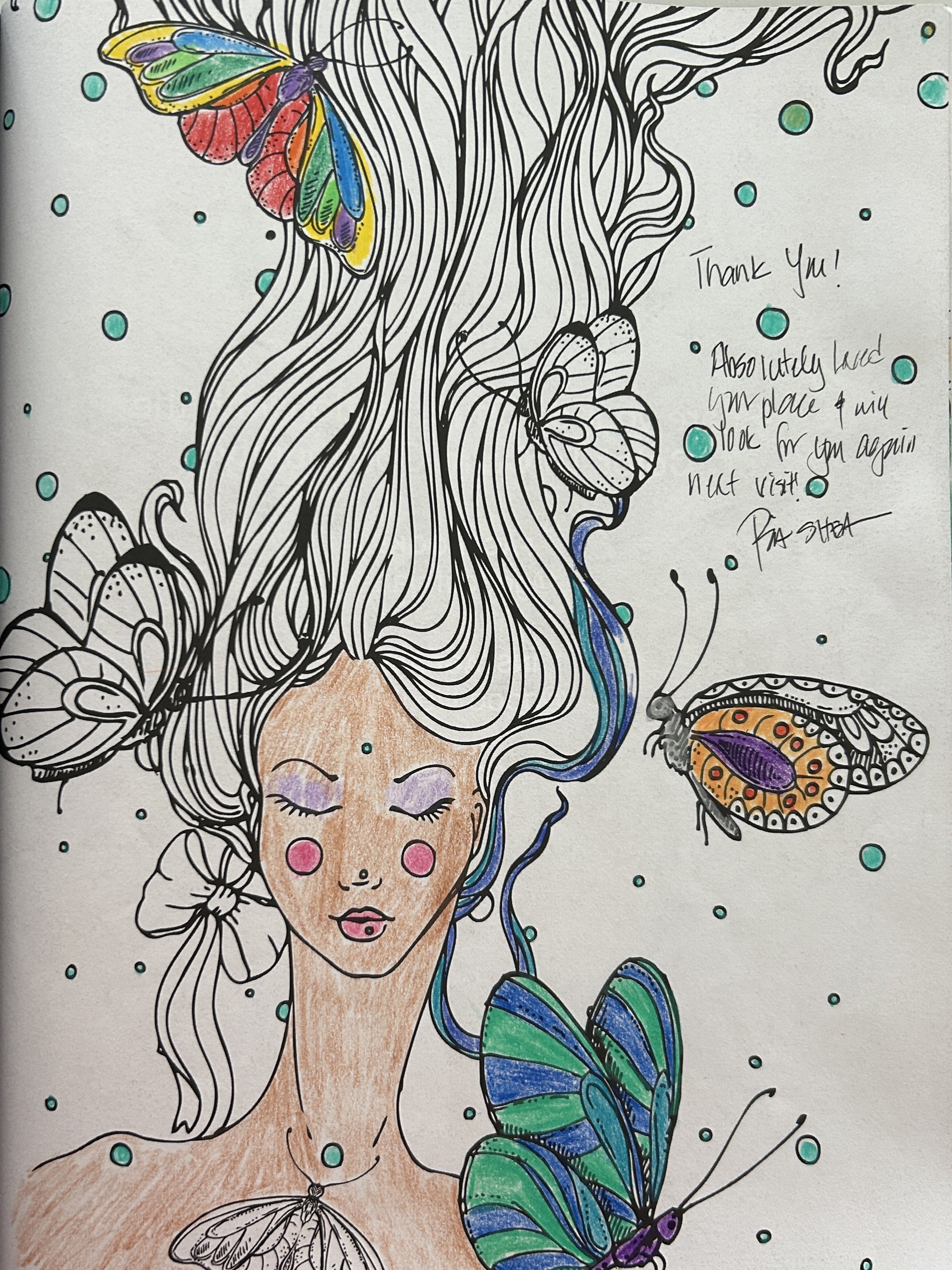 Coloring page of a woman with closed eyes and pink cheeks, surrounded by butterflies and insects, with loose flowing hair and a green and blue butterfly on her shoulder. There is a handwritten thank-you note on the right side.